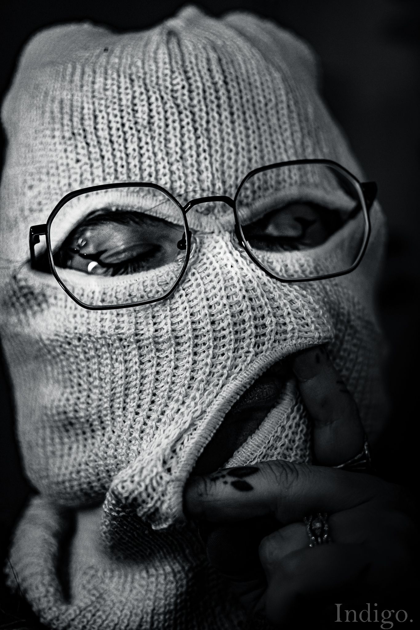 Artistic black and white portrait featuring eyeglasses and knitted fabric textures.