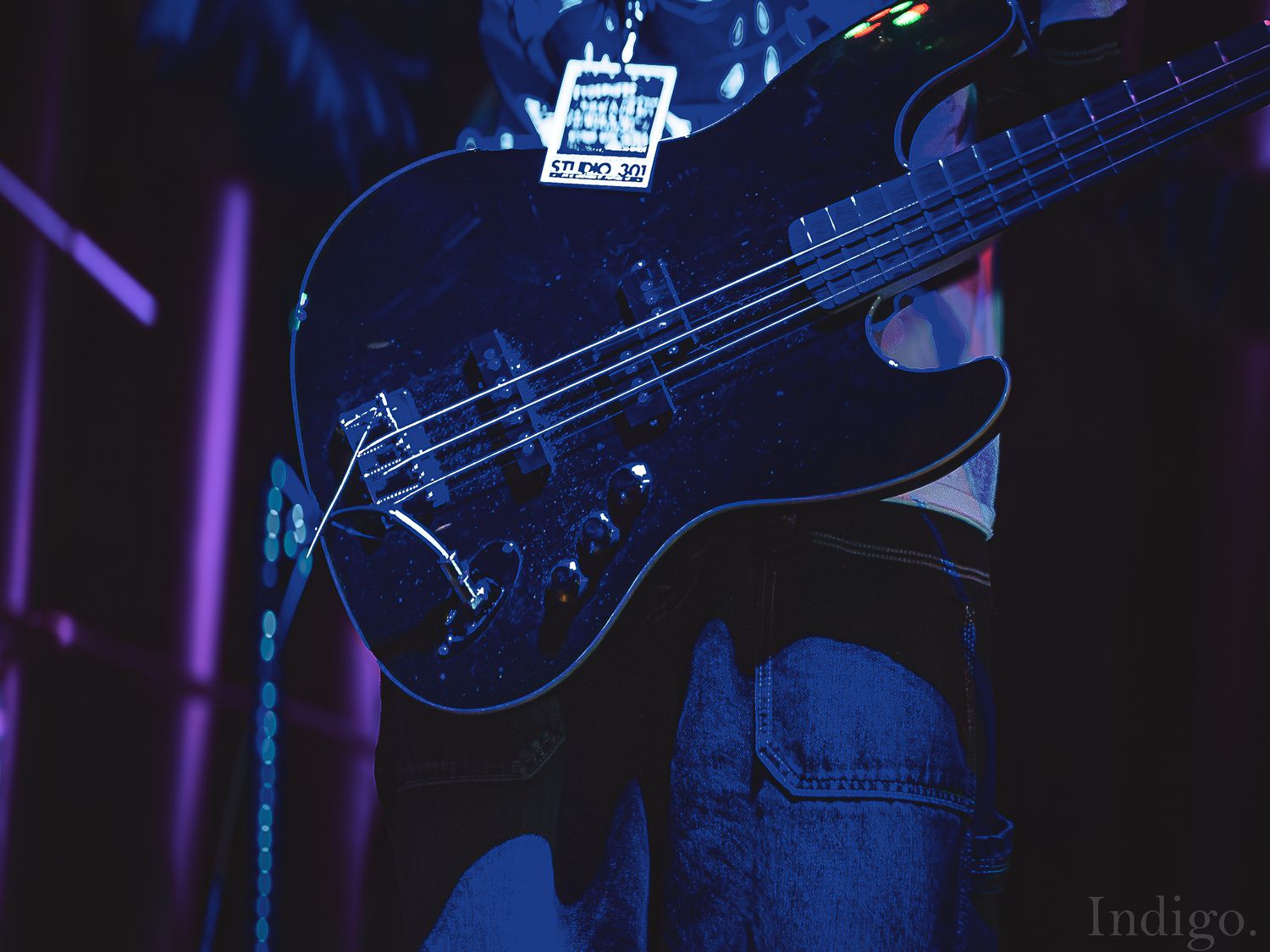 Dark silhouette of bass guitar and musical equipment against blue-lit stage background.
