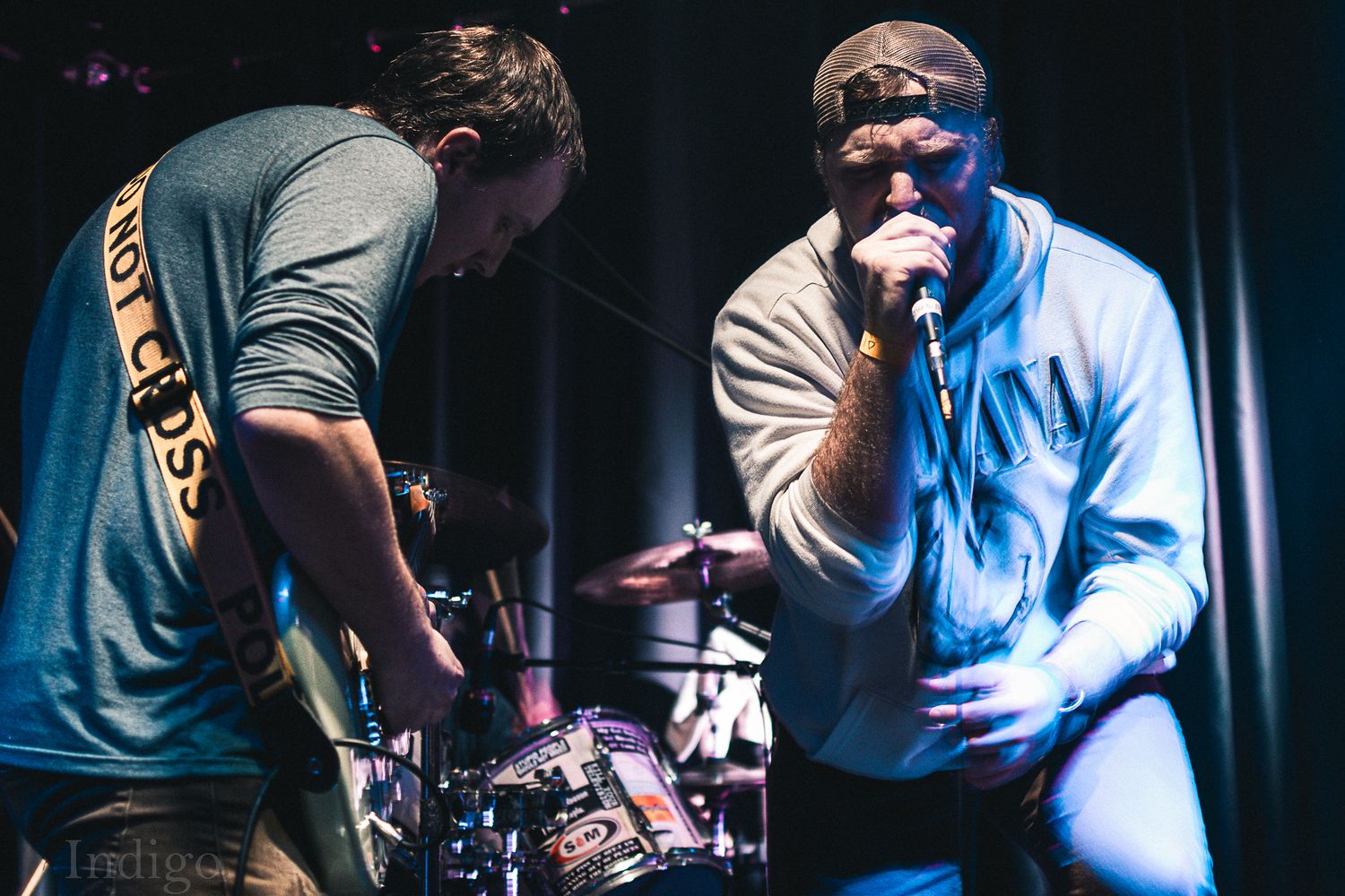 Musicians performing on stage with dramatic blue and white stage lighting effects.