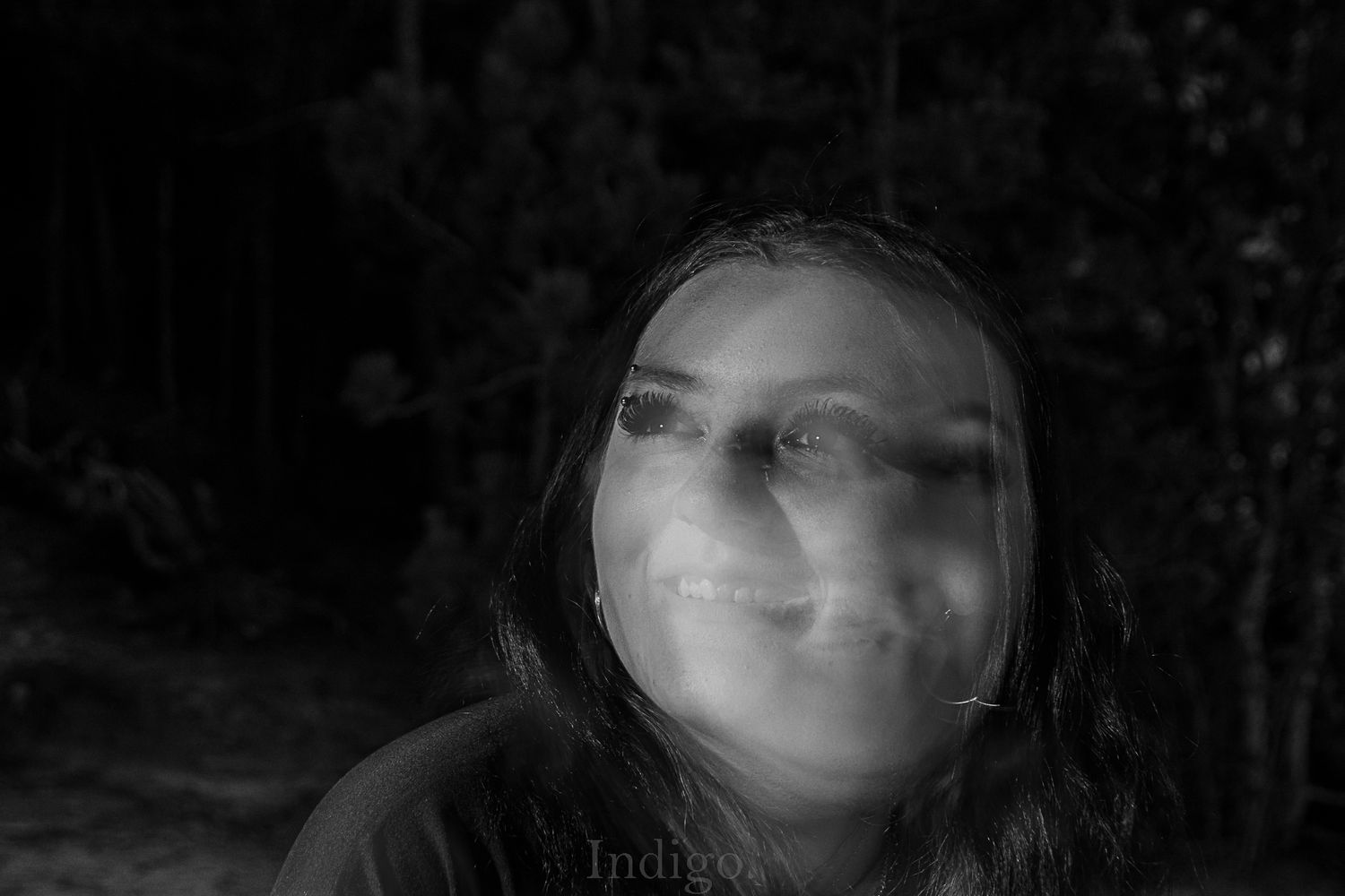 Dark artistic portrait with dramatic shadows and overlaid nature elements creating a dreamy effect.