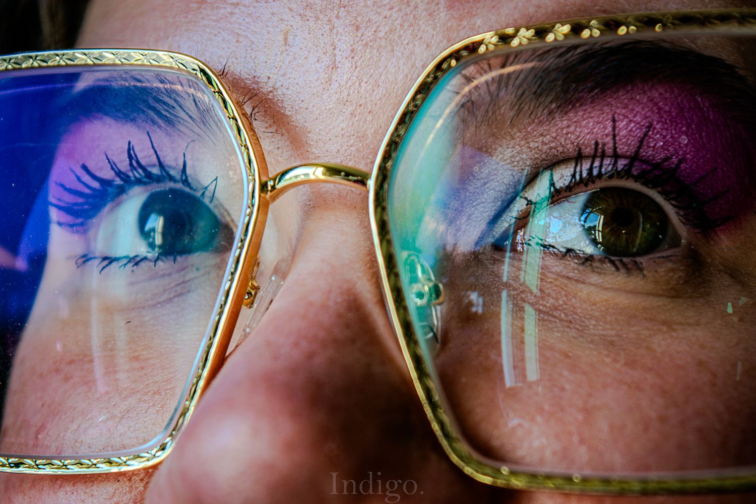 Extreme close-up of glasses frames reflecting colorful iridescent light.
