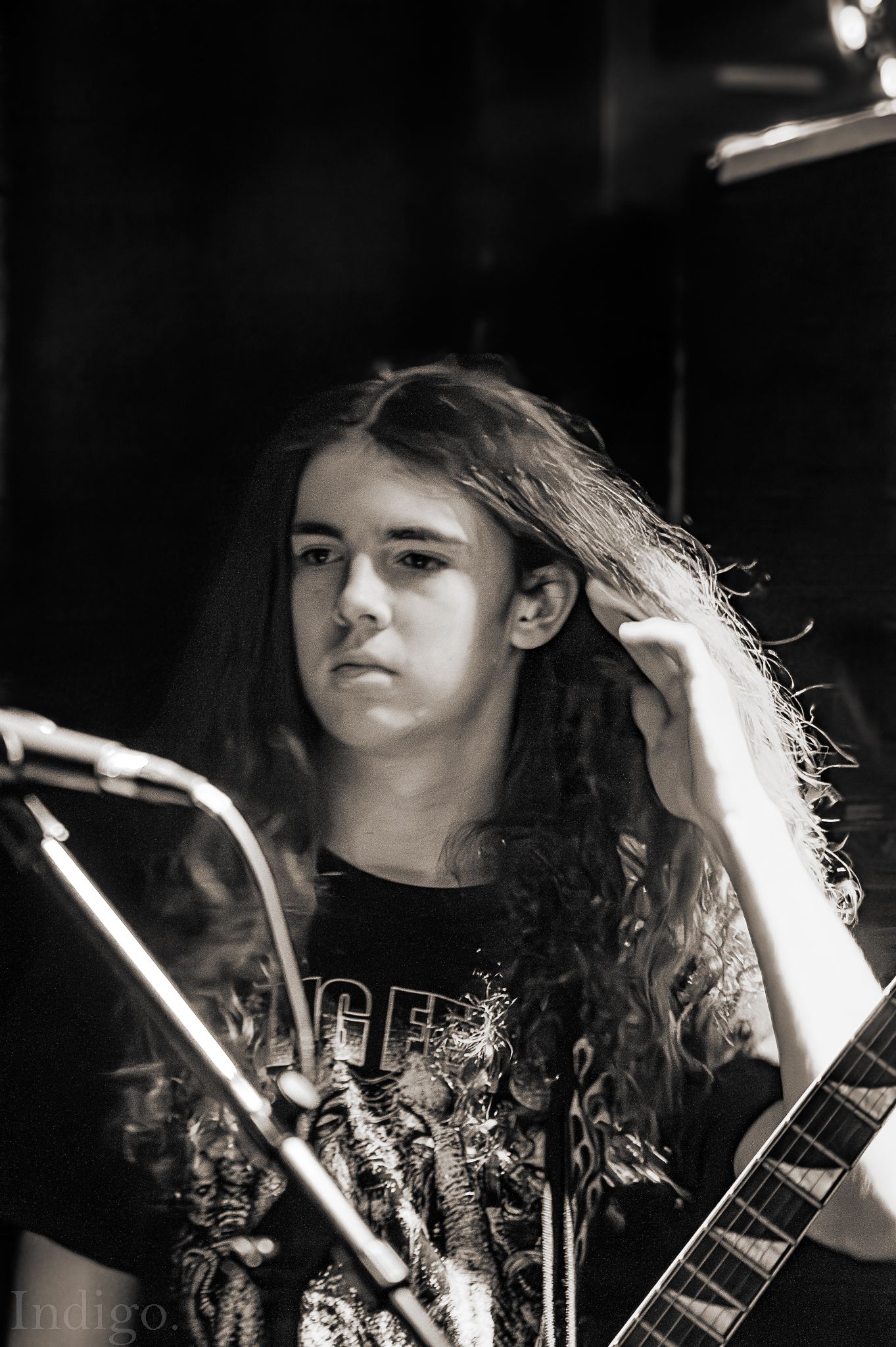 Dramatic black and white portrait of performer with long hair in stage lighting.