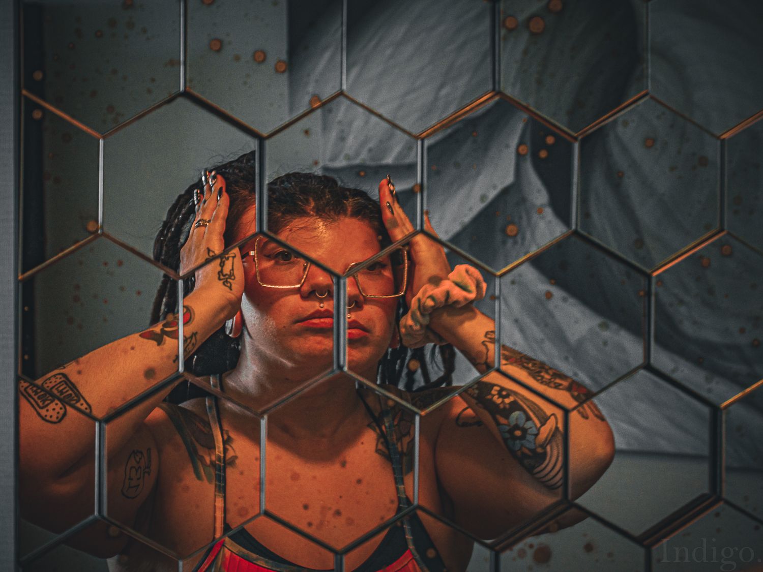 Artistic portrait with orange lighting against hexagonal geometric background creating moody atmosphere.
