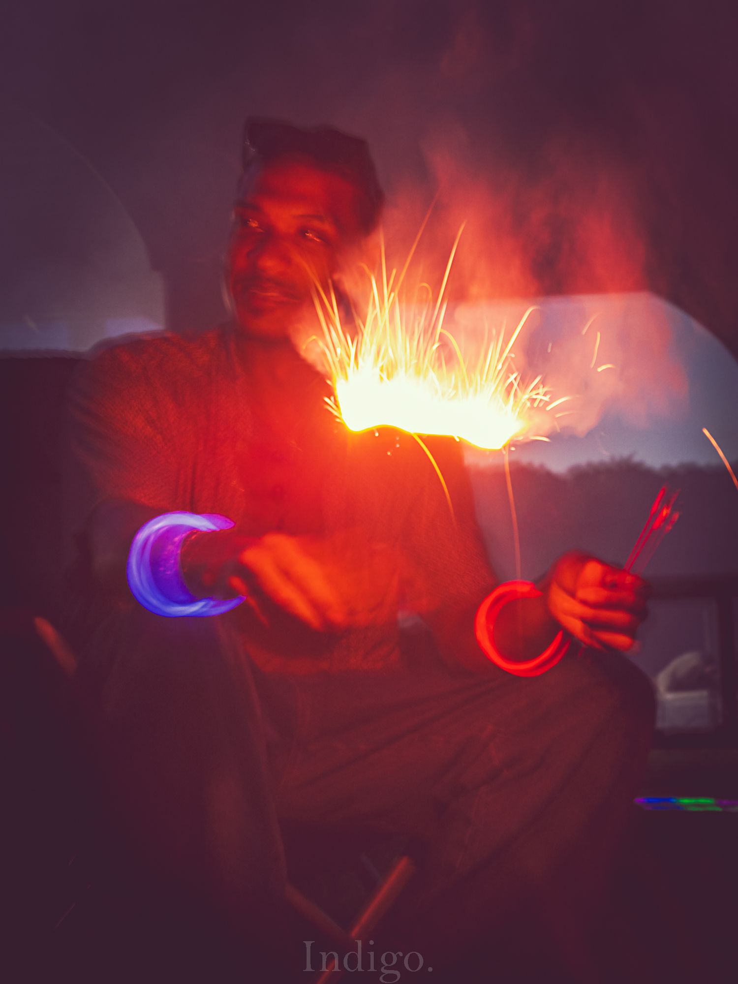 Person creates light trails with LED devices in a dark room bathed in red and blue illumination.
