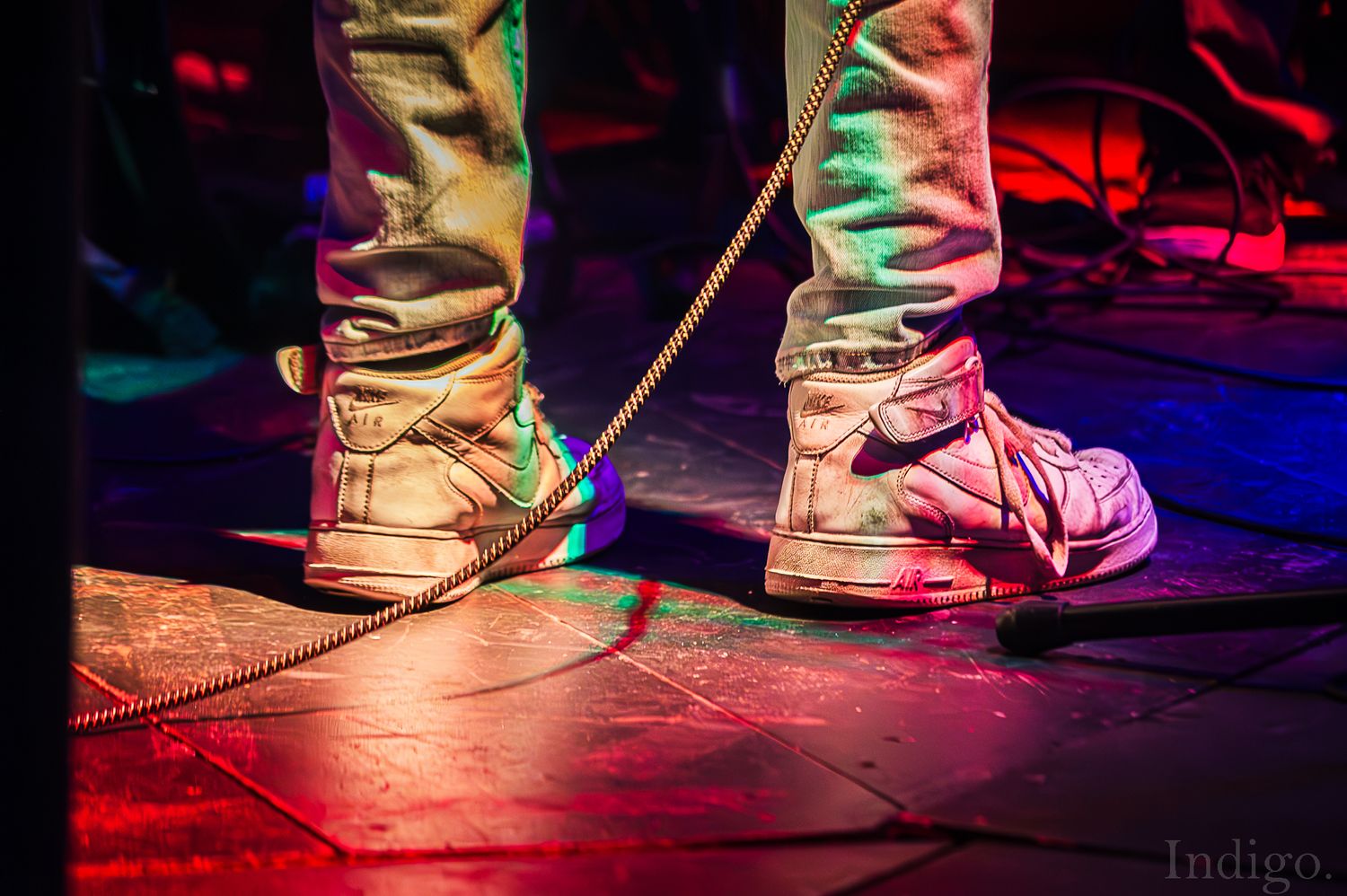 Close-up of performer's shoes on colorfully lit stage during concert.