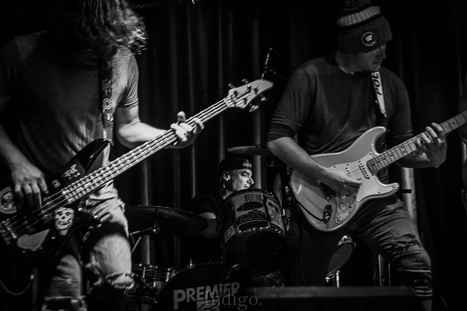 Musicians playing bass guitars in dark concert lighting creating dramatic silhouettes.