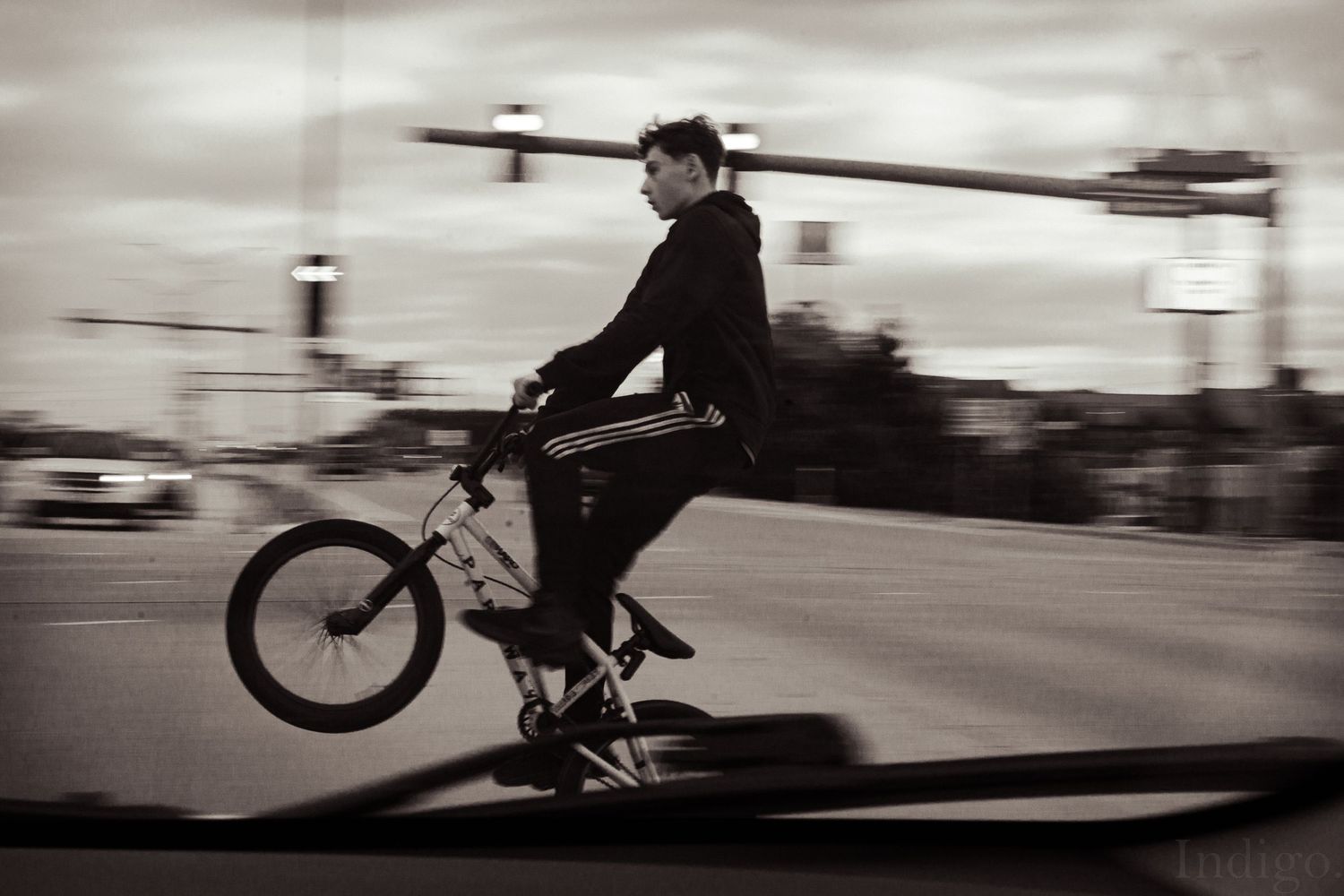 Motion blur capture of a cyclist riding through an urban street in black and white.