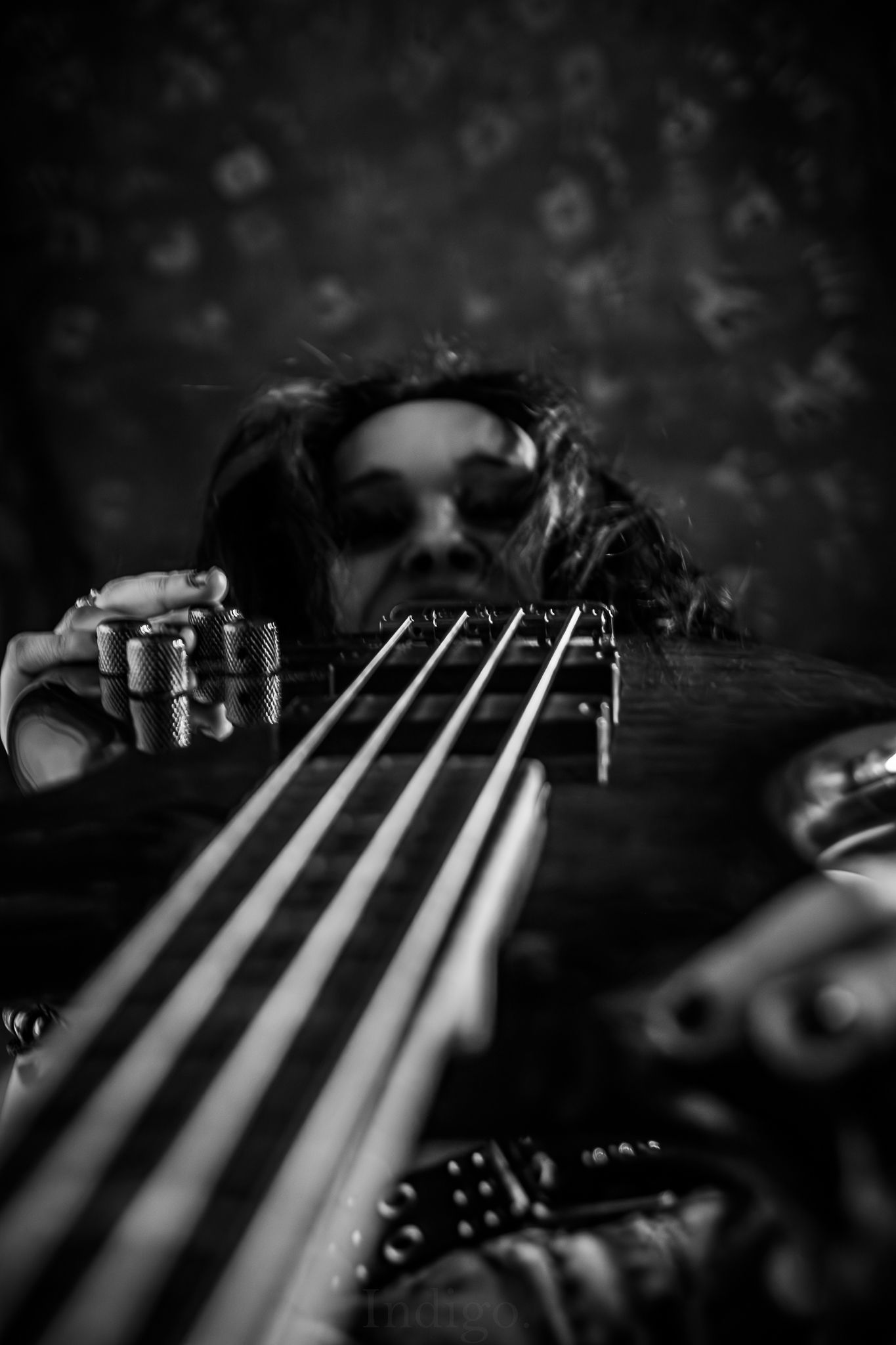 Close-up black and white macro shot of guitar strings and tuning pegs.
