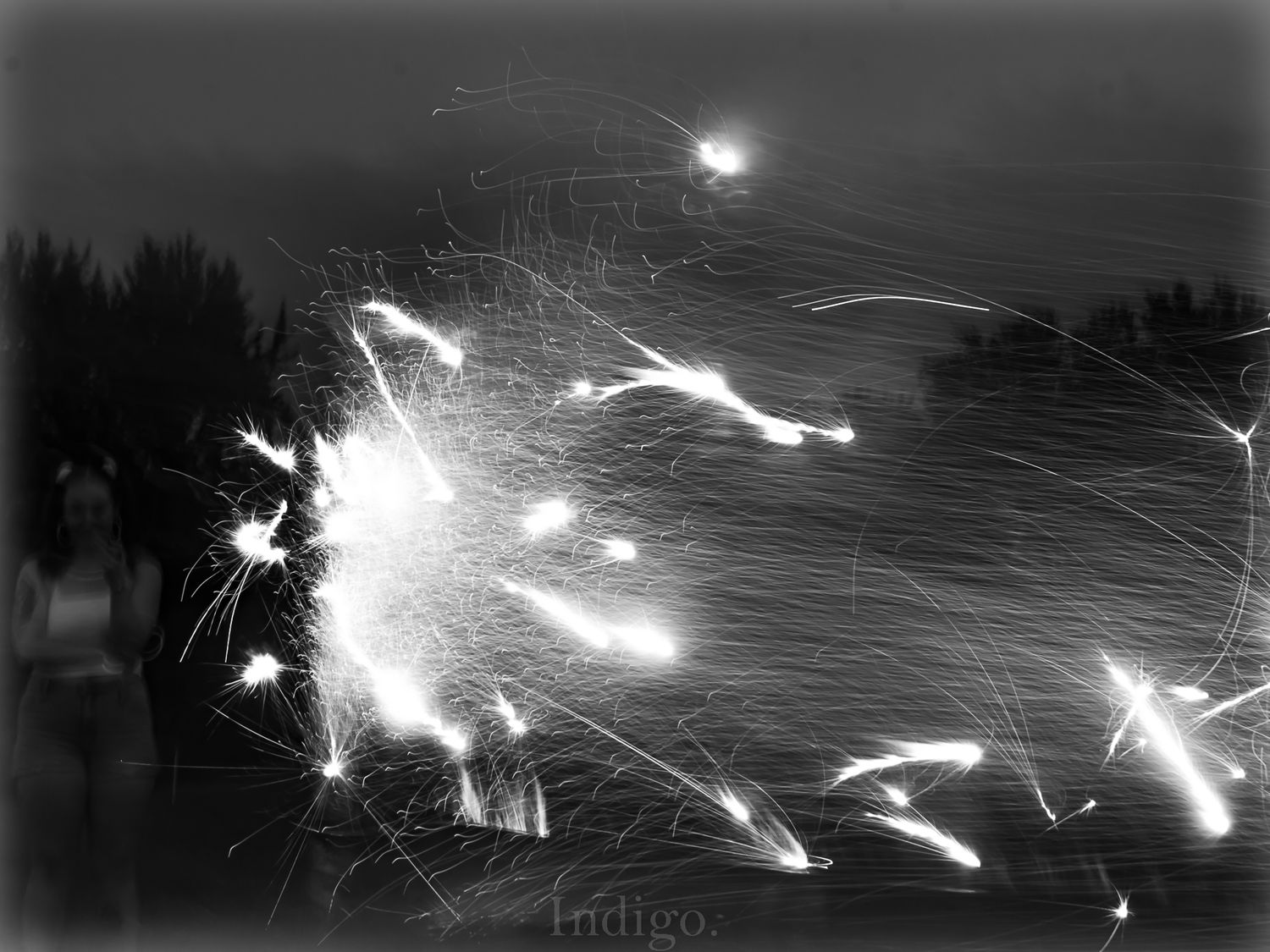 Abstract black and white long exposure photograph of sparks and light trails against a dark sky.