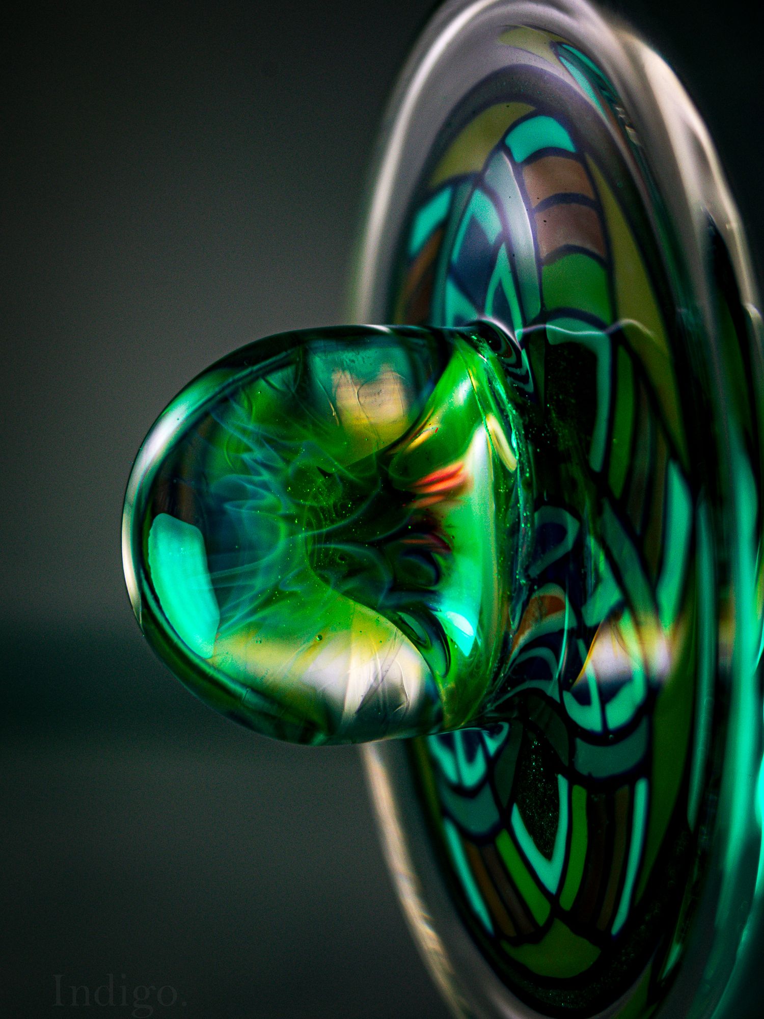 Close-up shots of a glass pipe with swirling green illumination against a dark background.