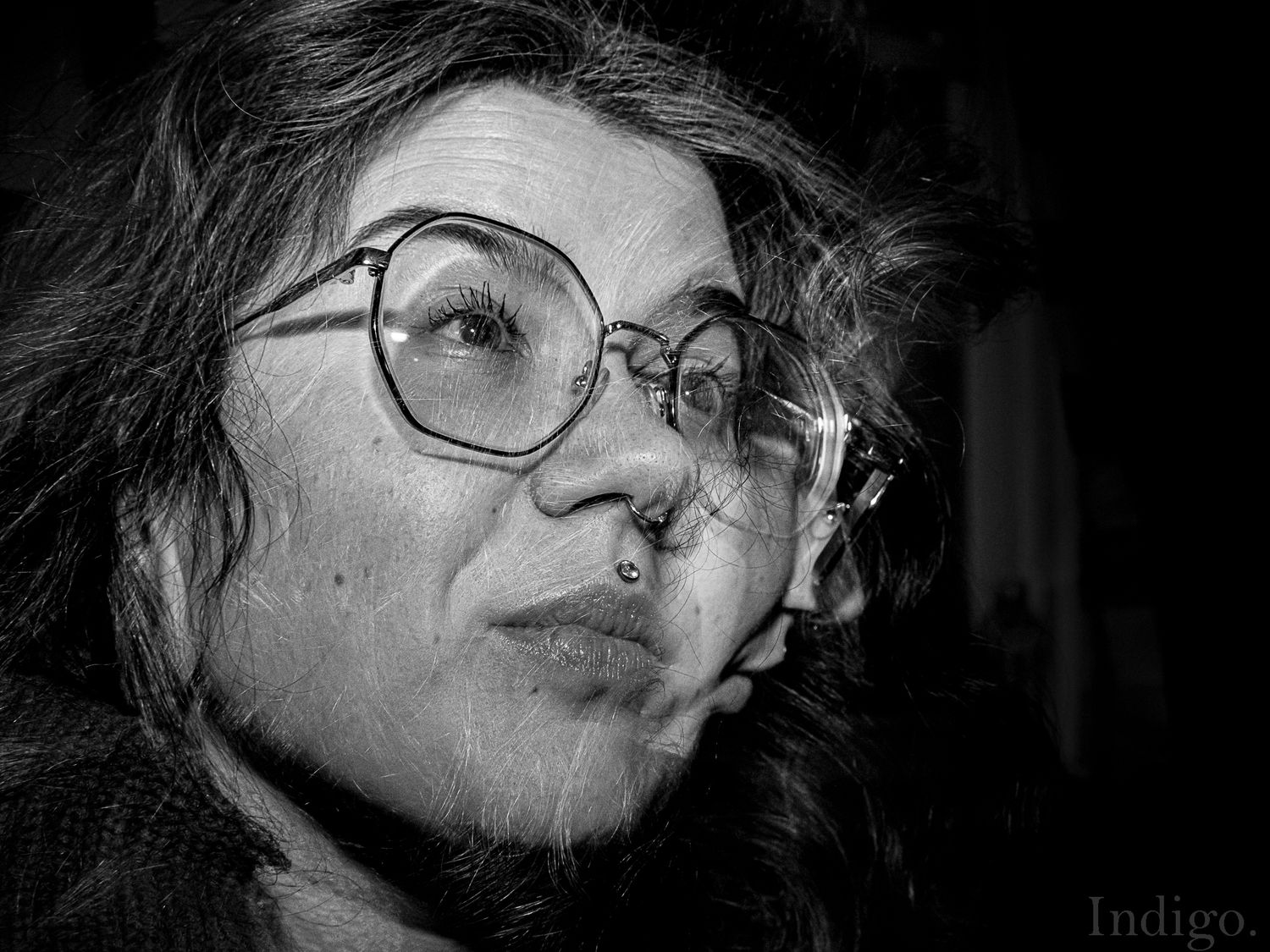 Black and white close-up portrait with round glasses in dramatic lighting.