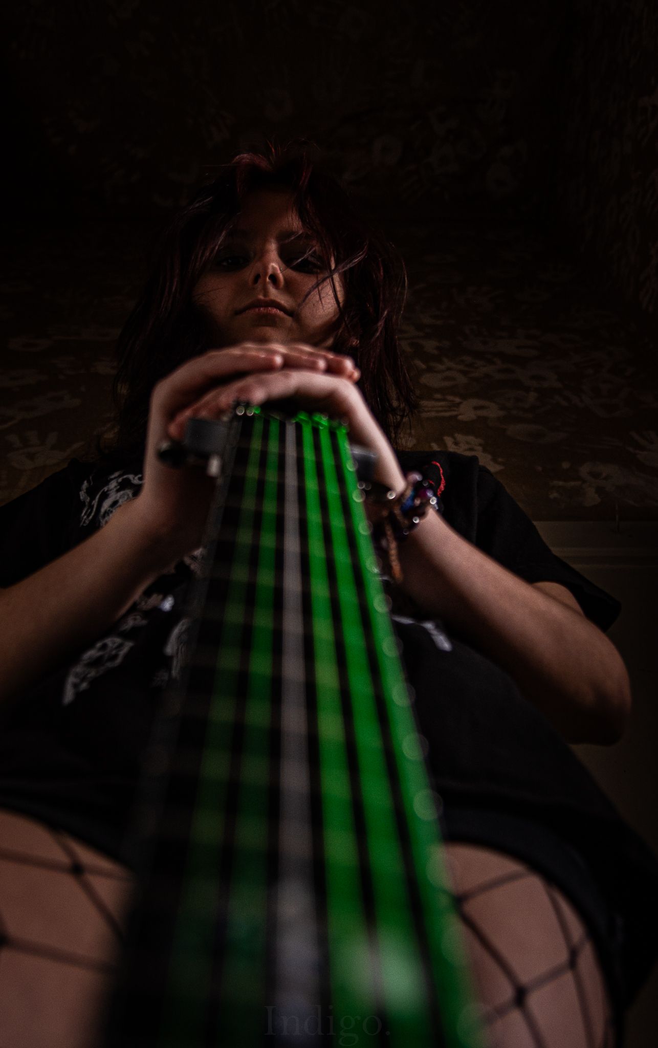 Neon green guitar strings glowing in dramatic low-key lighting.