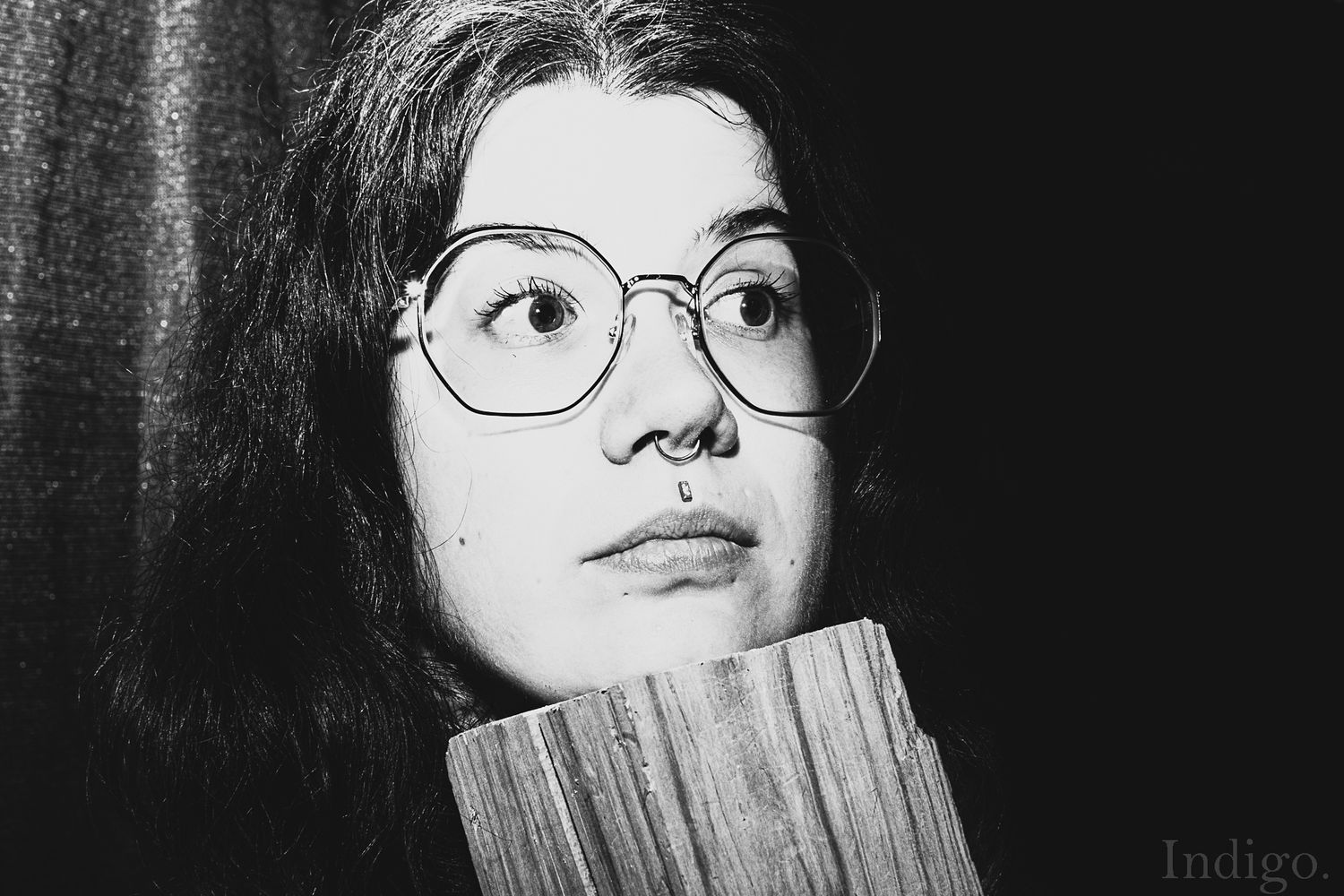 High contrast black and white portrait shot with dramatic lighting and round glasses.