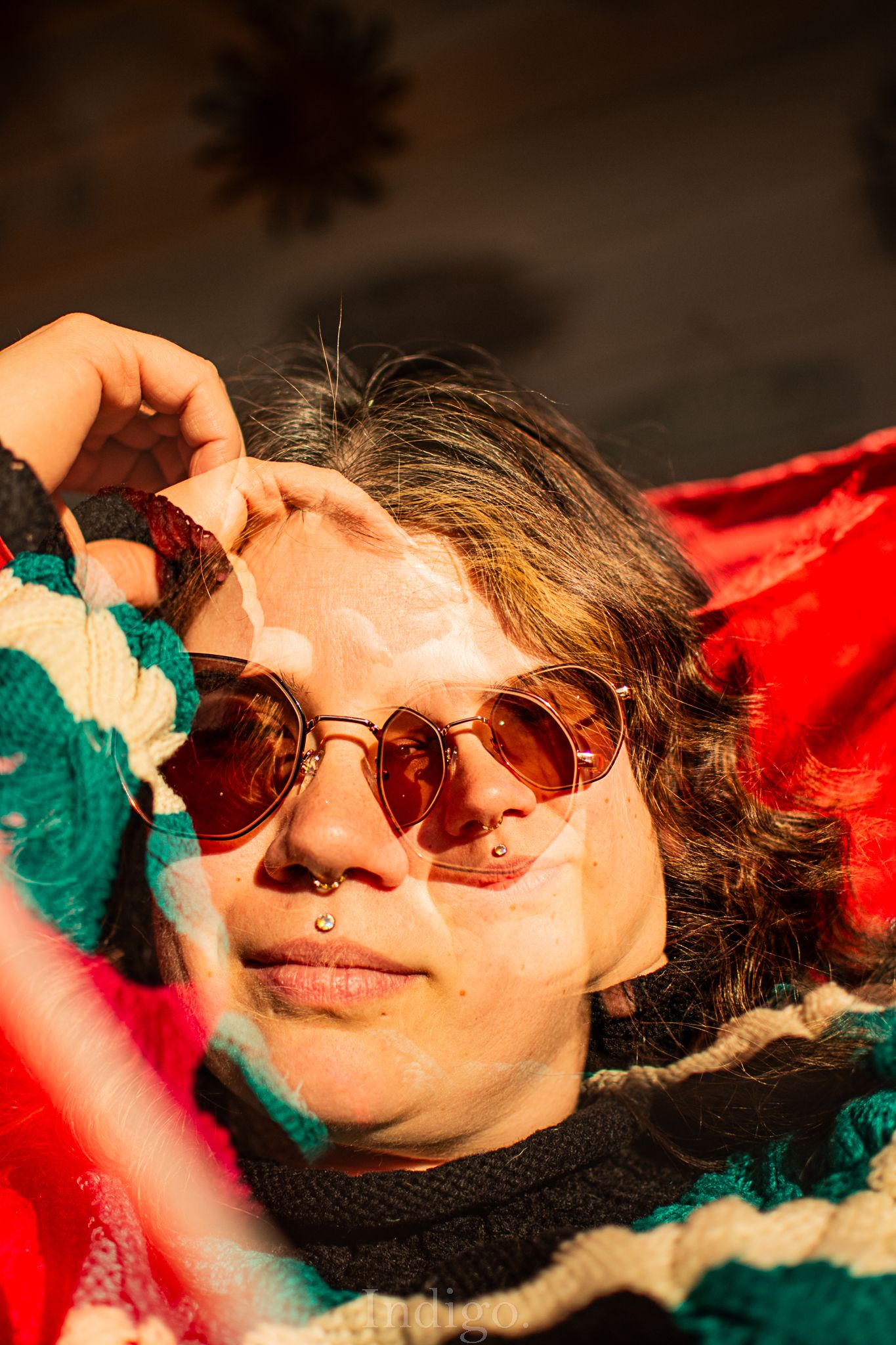Sunlit portrait with vintage sunglasses and colorful textile background.