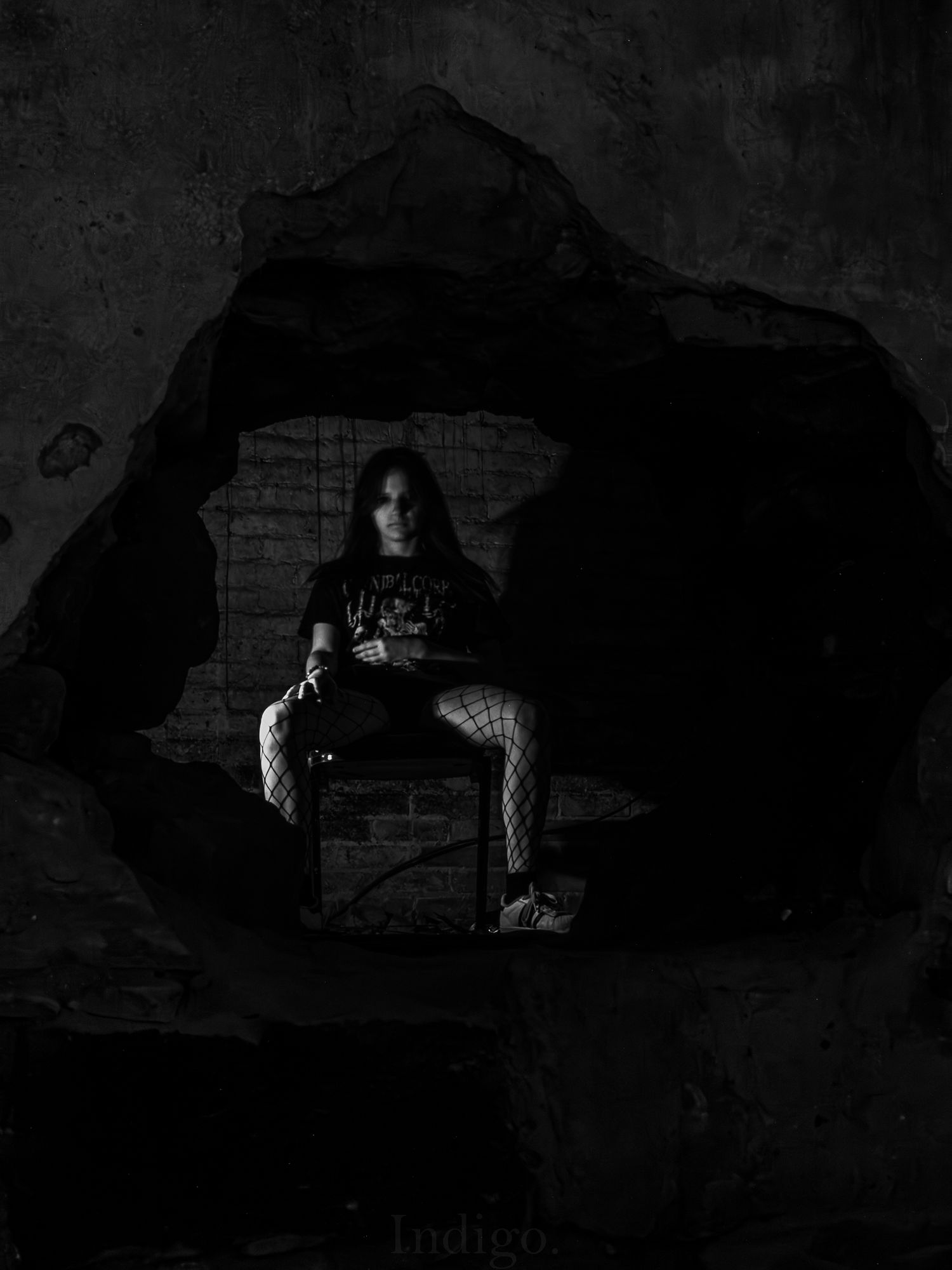 Silhouetted person sitting in brick alcove with dramatic lighting.