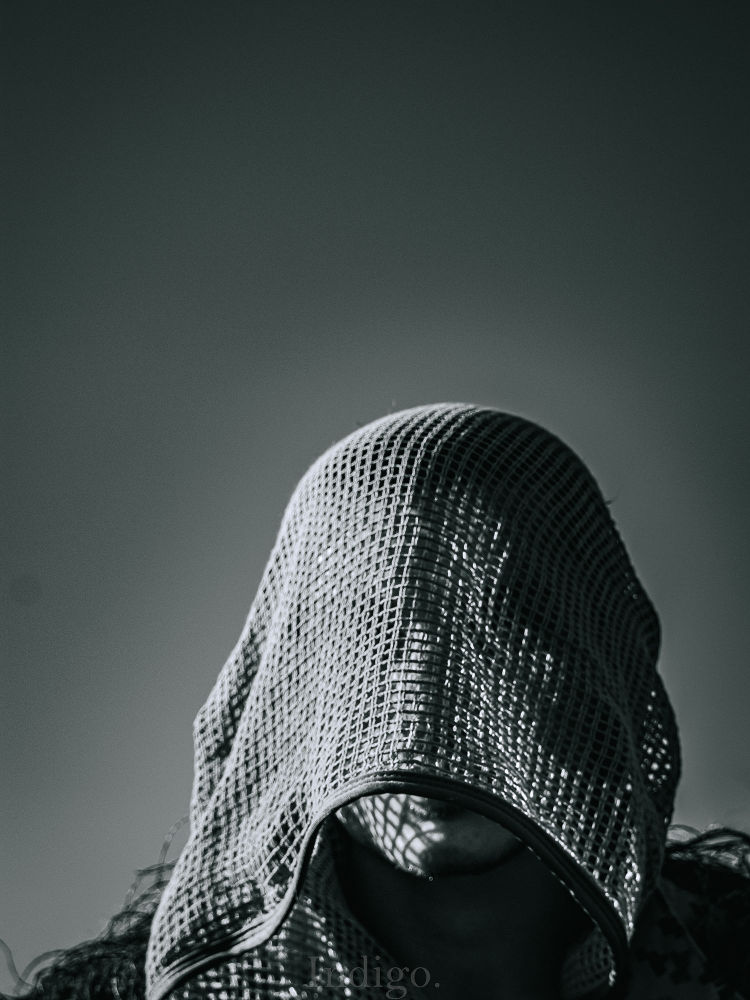 Dark silhouette of a knit beanie or winter hat against a moody gradient background.