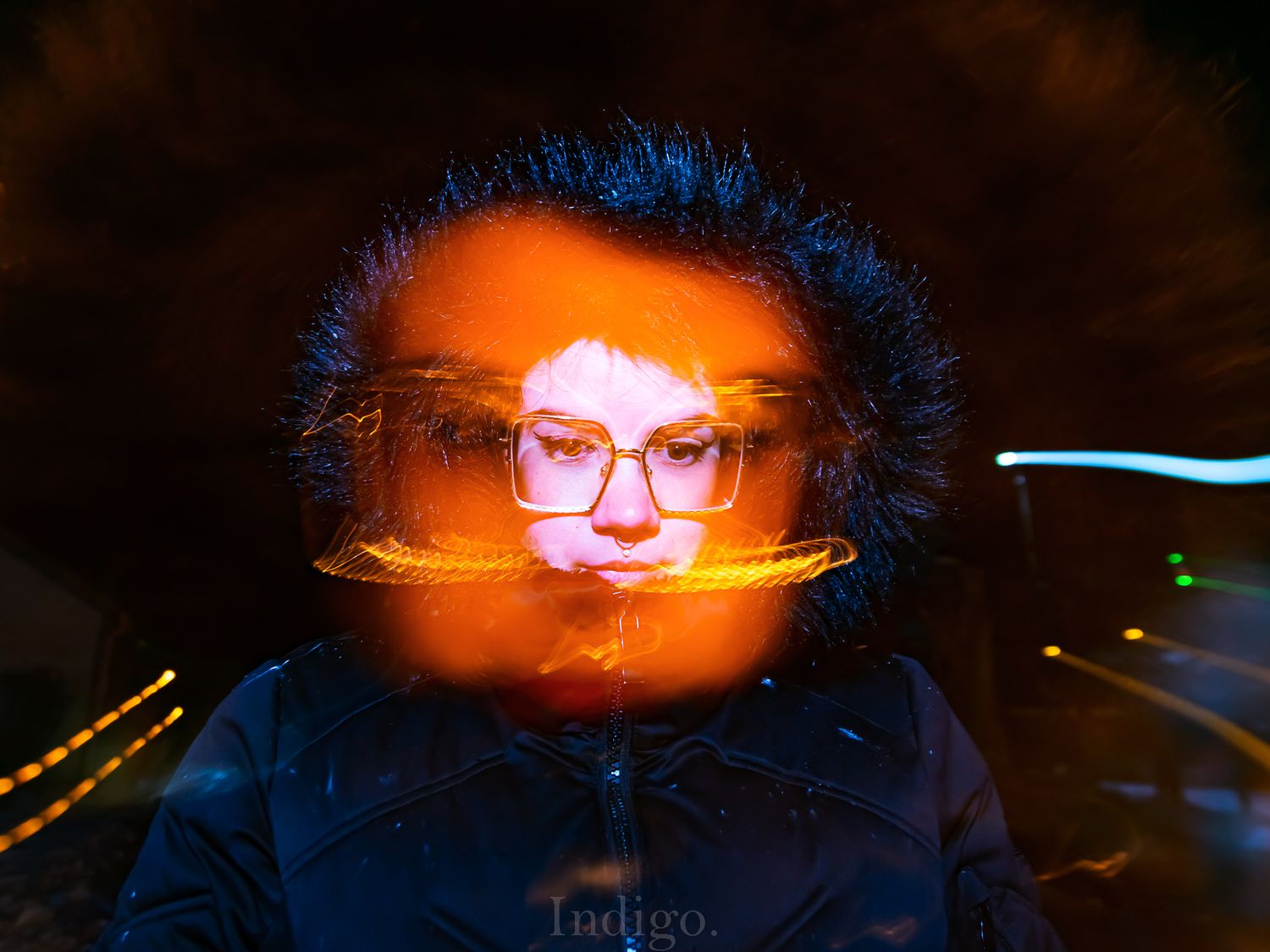 Long exposure light painting creates a glowing orange orb effect against a dark background.