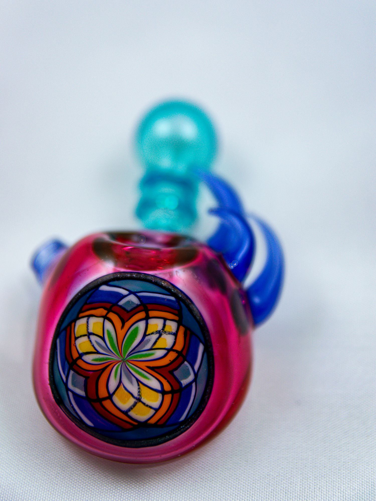 Decorative glass pipe with colorful floral pattern designs in pink and blue tones.