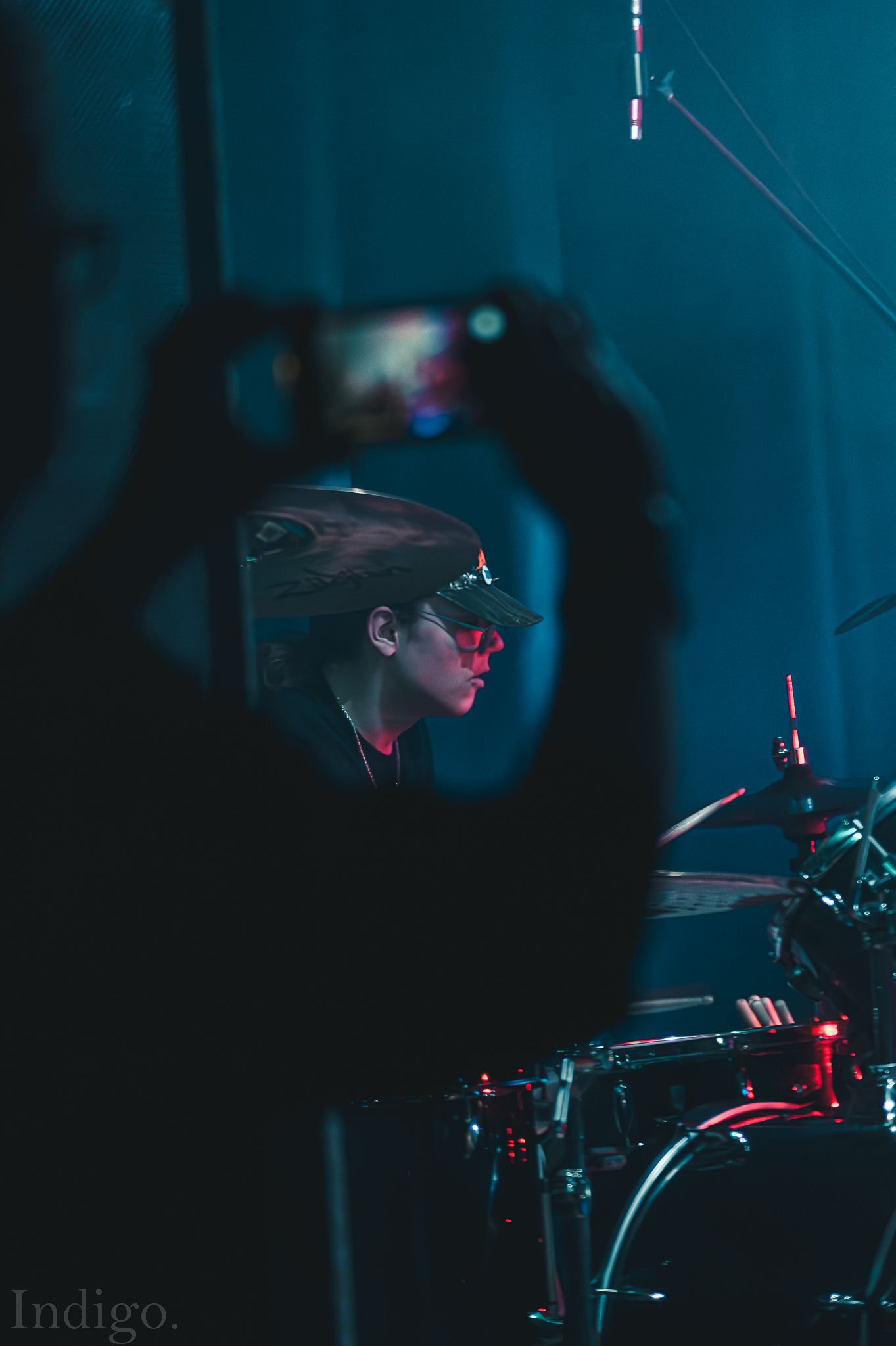 Silhouetted musician performing on stage against deep blue lighting background.