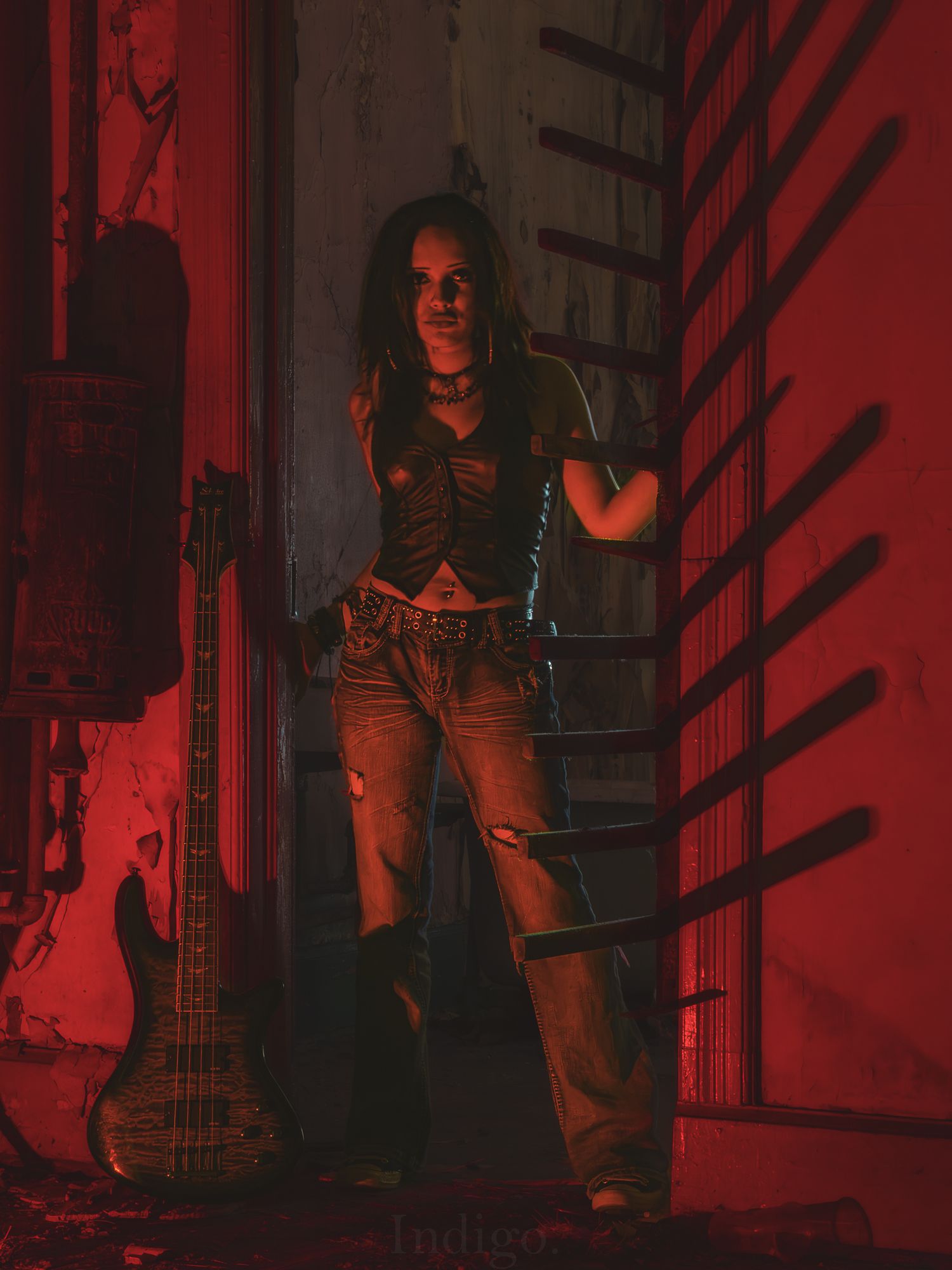 Figure with guitar standing in hallway bathed in dramatic red lighting.
