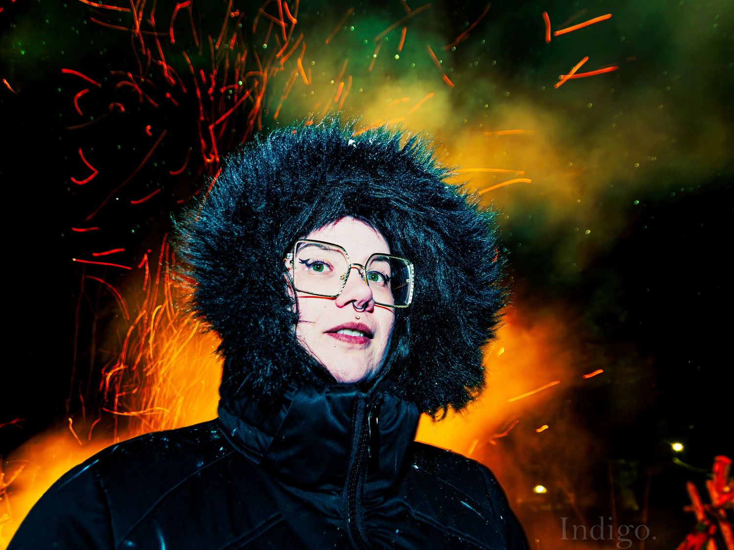 Dramatic nighttime portrait with fur-lined hood against fiery background.
