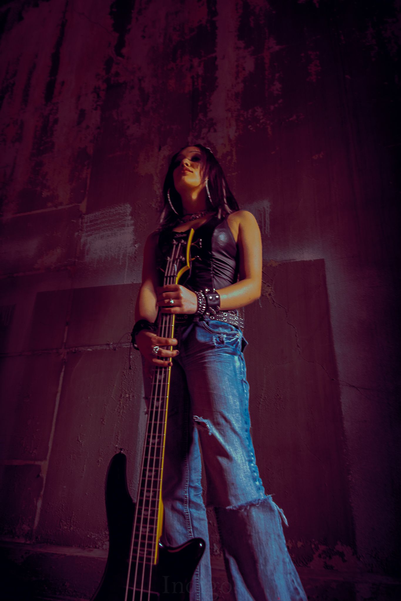 Bass guitarist in denim performing on a dimly lit purple stage.