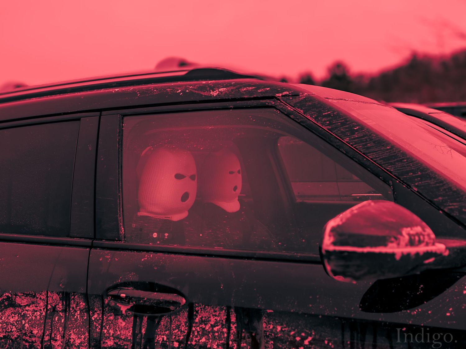 Silhouettes visible through car window against pink sunset sky.