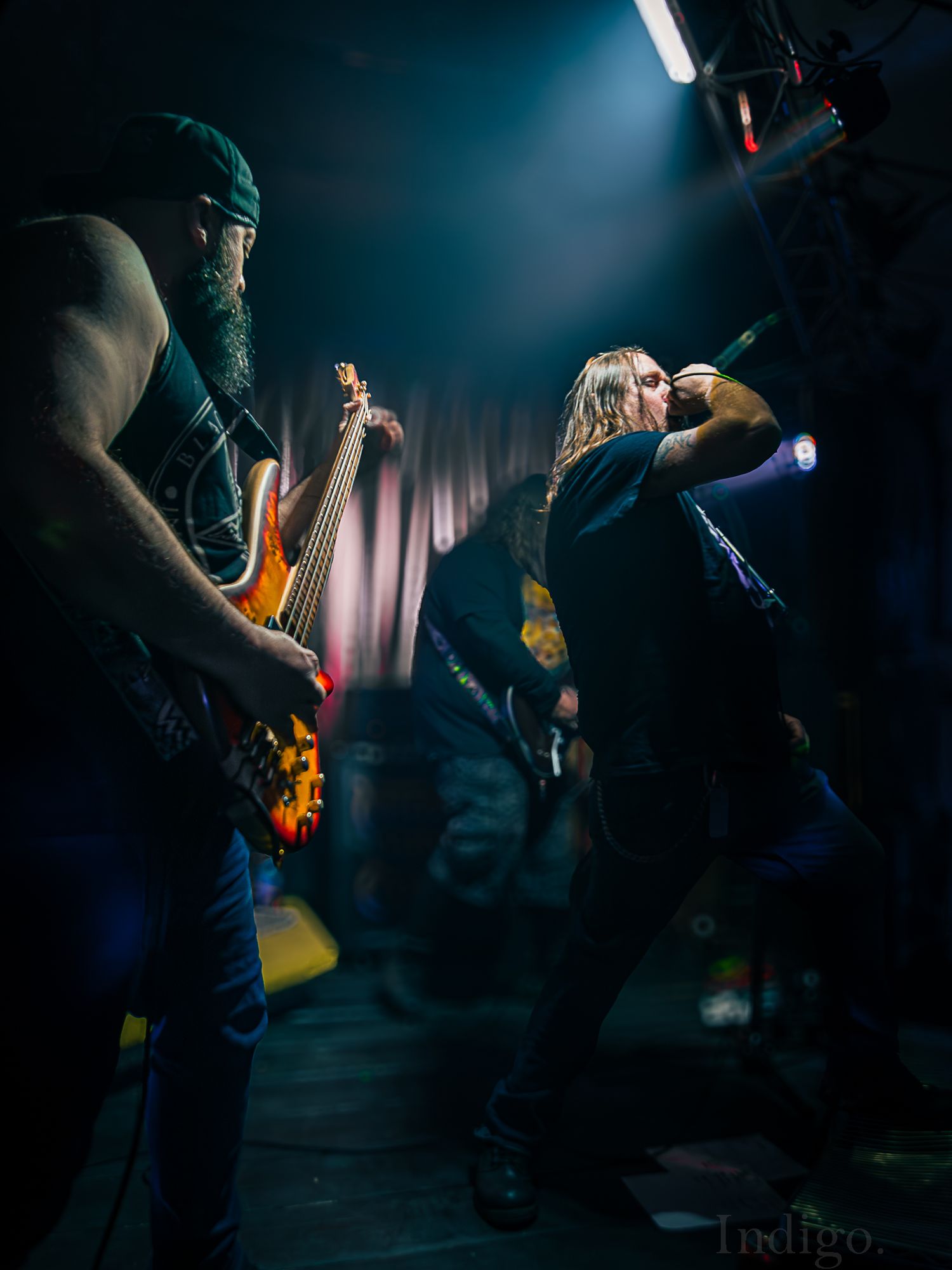 Low-angle concert photography capturing musicians performing in moody blue lighting.