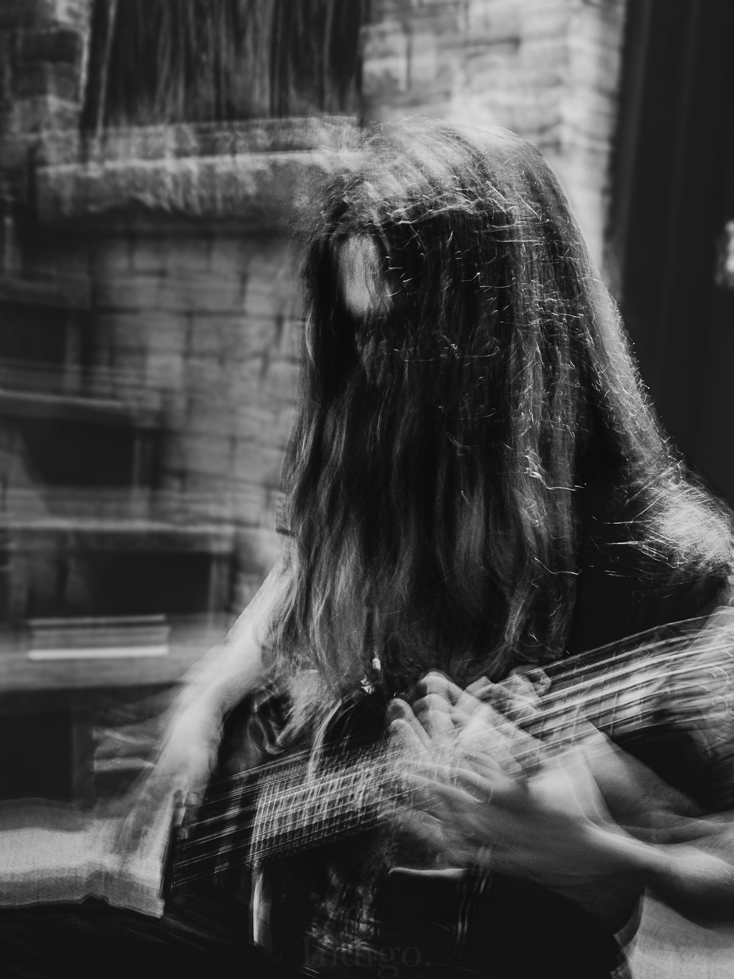 Artistic motion blur photo of musician playing bass guitar in black and white.