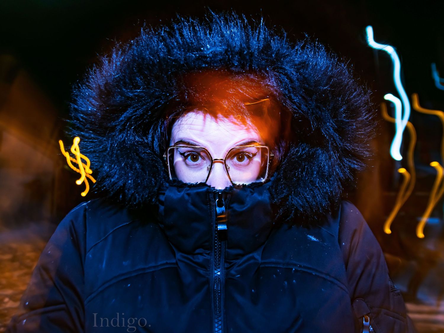 Winter portrait in dark lighting with blue fur hood and neon reflections.