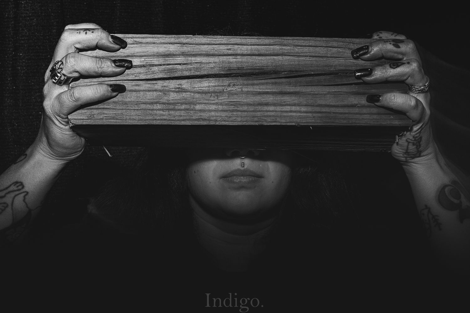 Dramatic black and white photo of hands holding old books covering part of the frame.