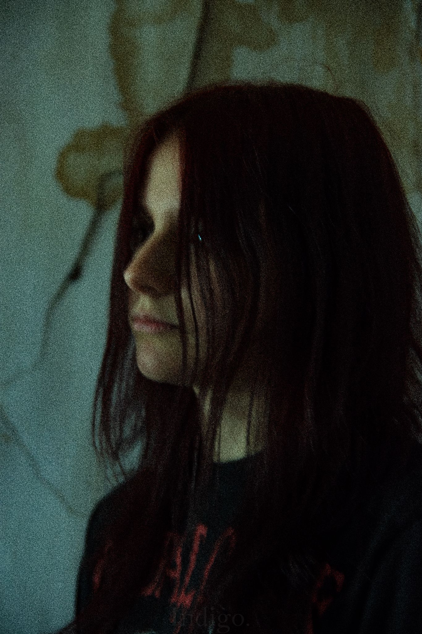 Atmospheric low-key portrait with teal toned lighting and dark shadows.