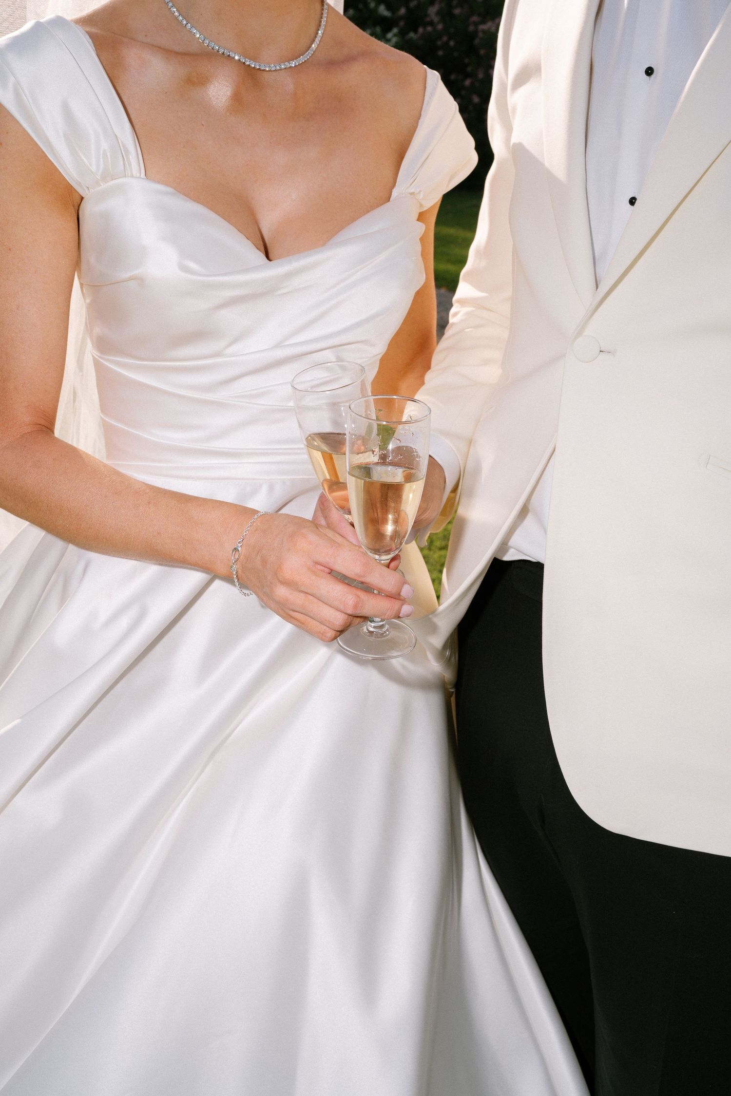 Close-up details of elegant white wedding attire at an outdoor celebration.