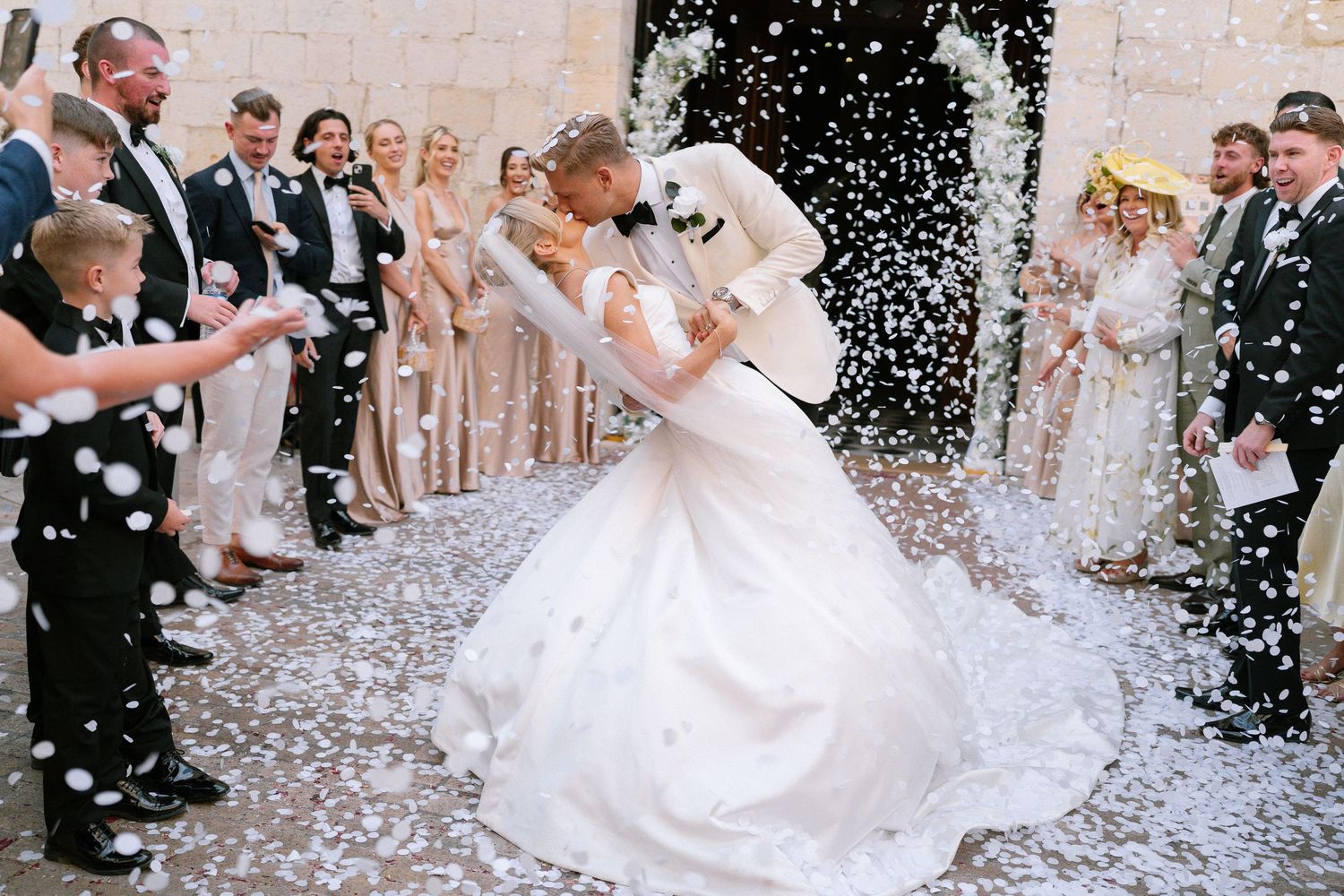 Wedding celebration with confetti being thrown in an outdoor courtyard.