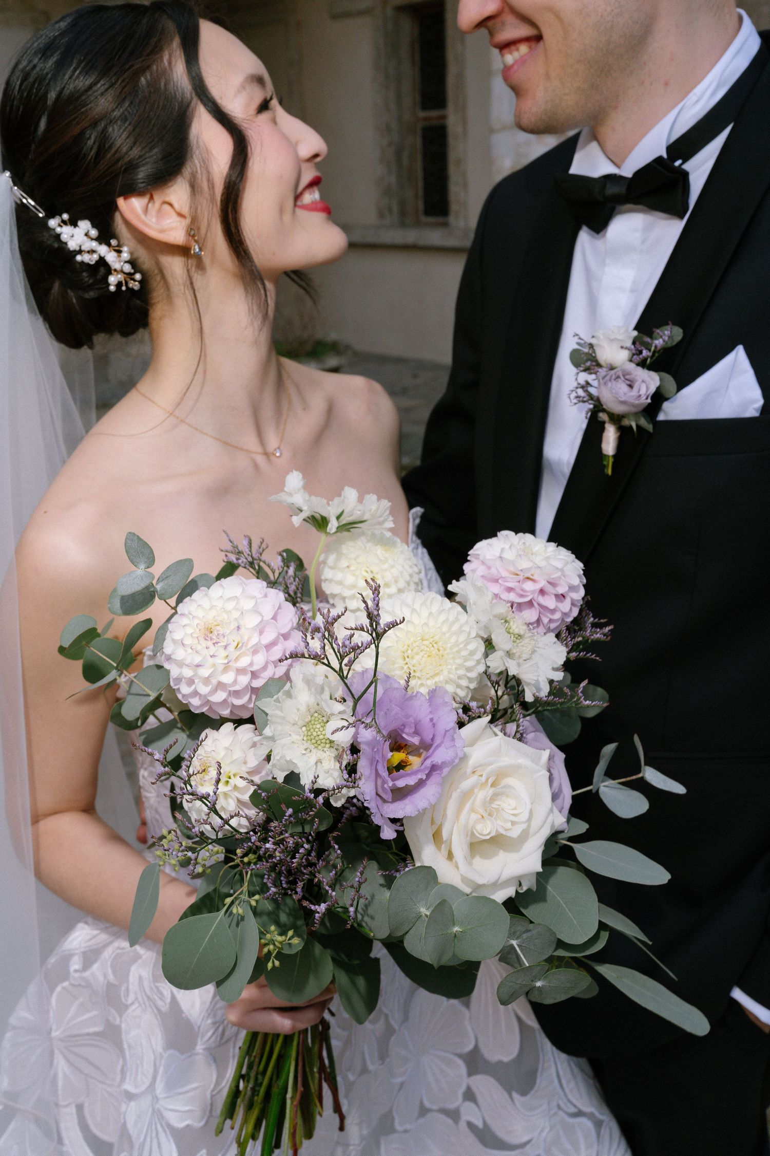 Elegant wedding bouquet featuring white and purple flowers with eucalyptus greenery.