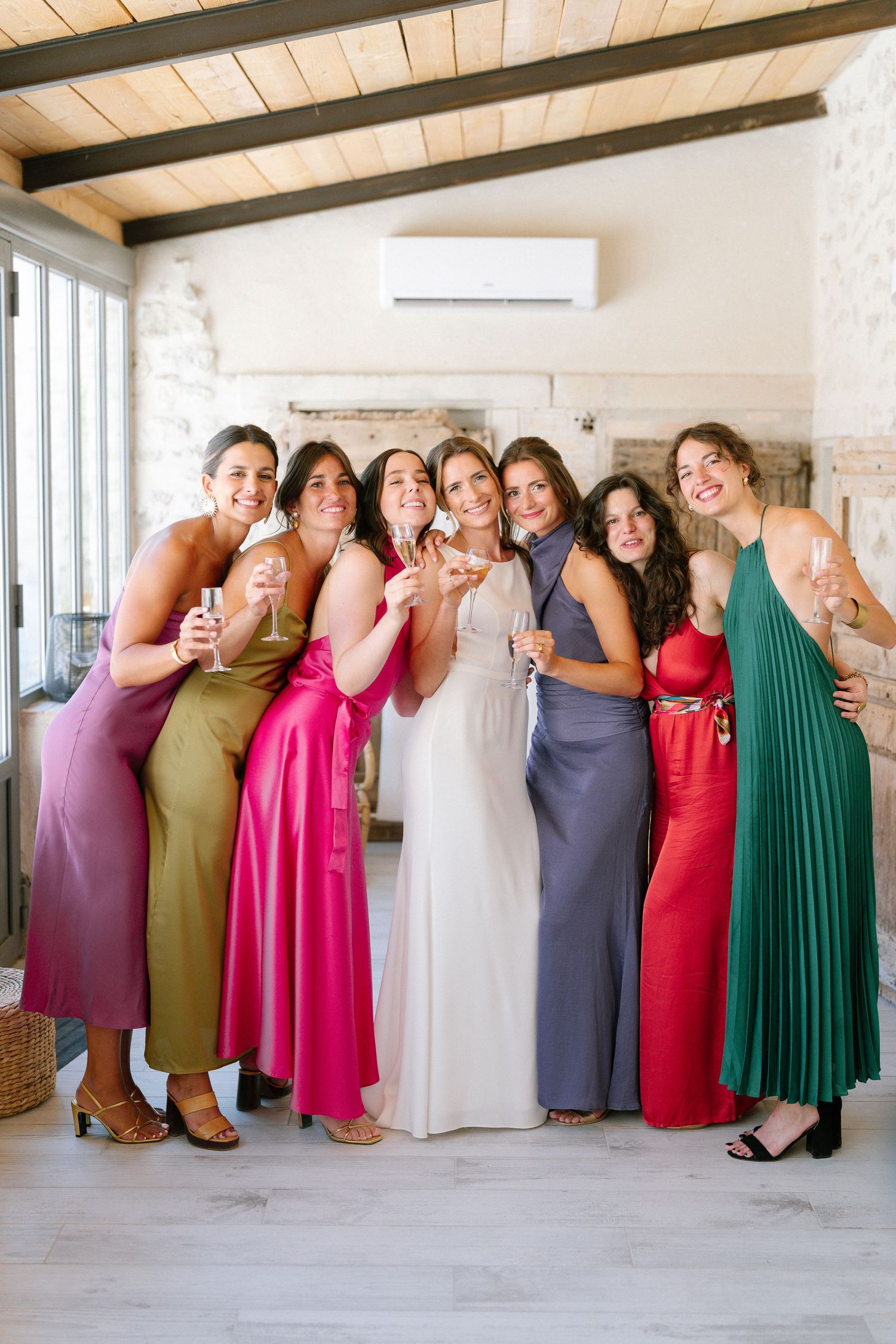 Bridesmaids in colorful dresses posing together for a fun group photo.