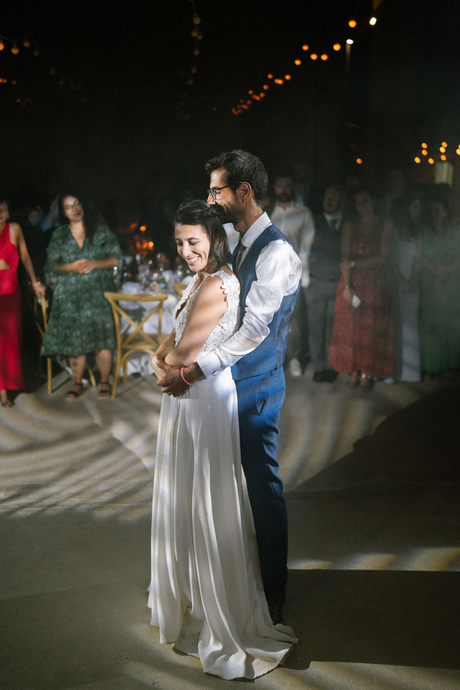Couple shares their first dance at an evening wedding reception with twinkle lights.