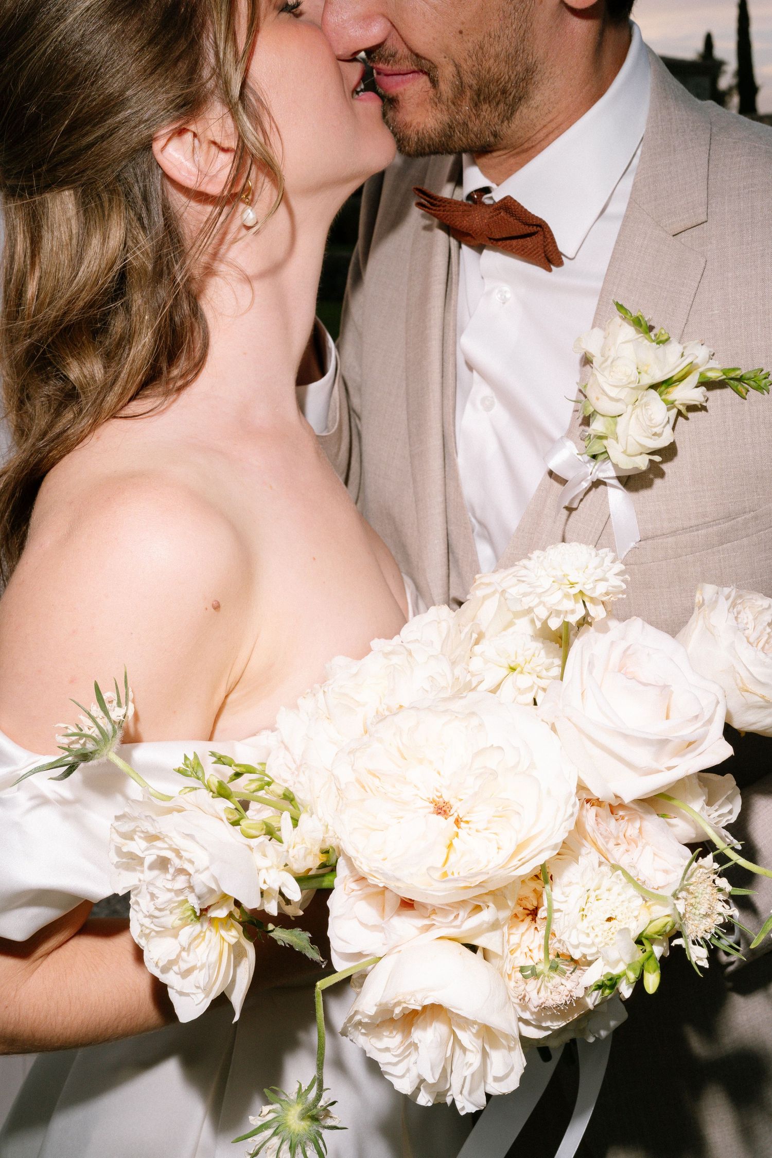 Intimate wedding portrait with soft peach rose bouquet and gentle embrace.