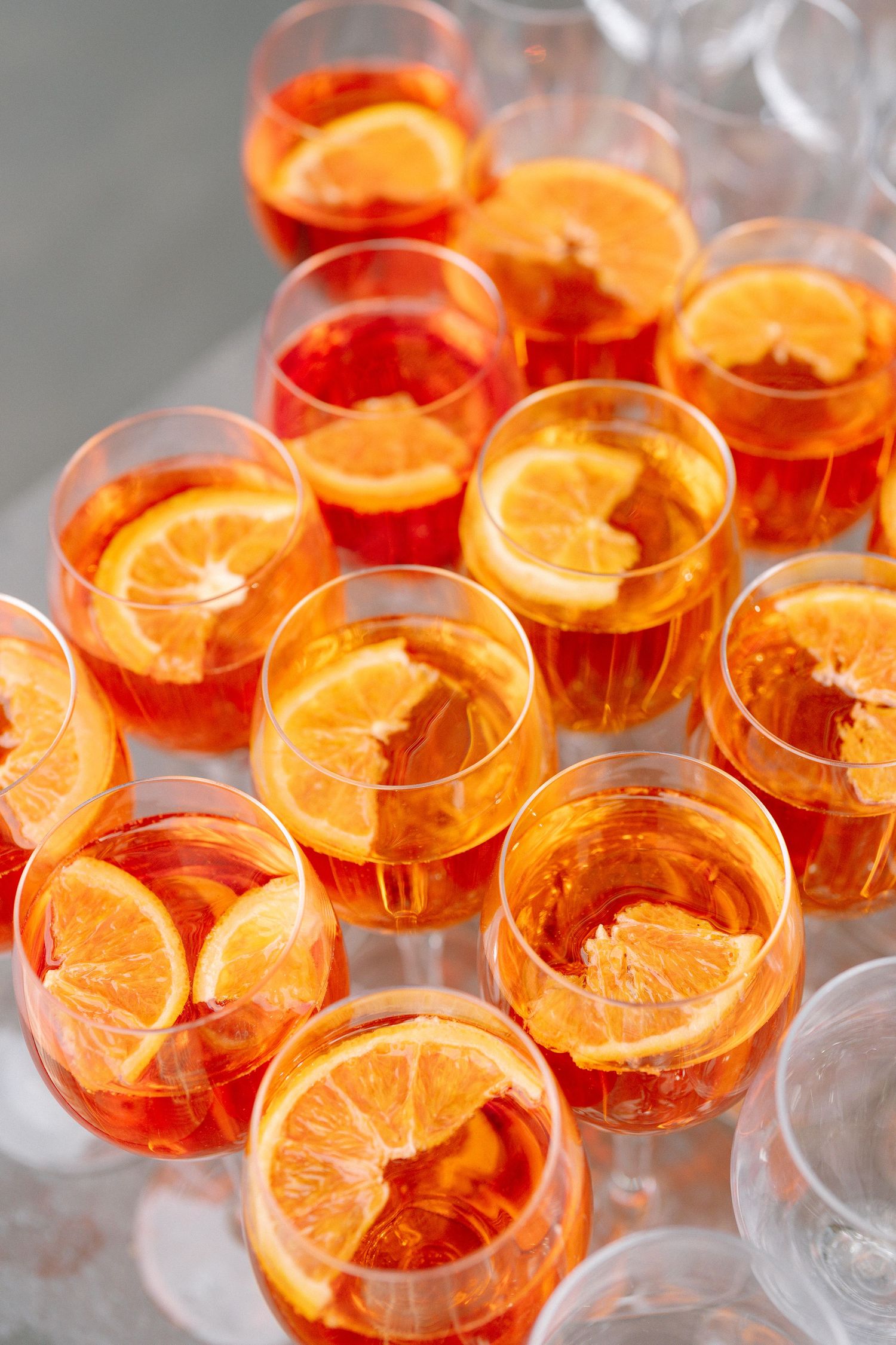 Orange-colored cocktails in clear glasses arranged for a wedding reception.