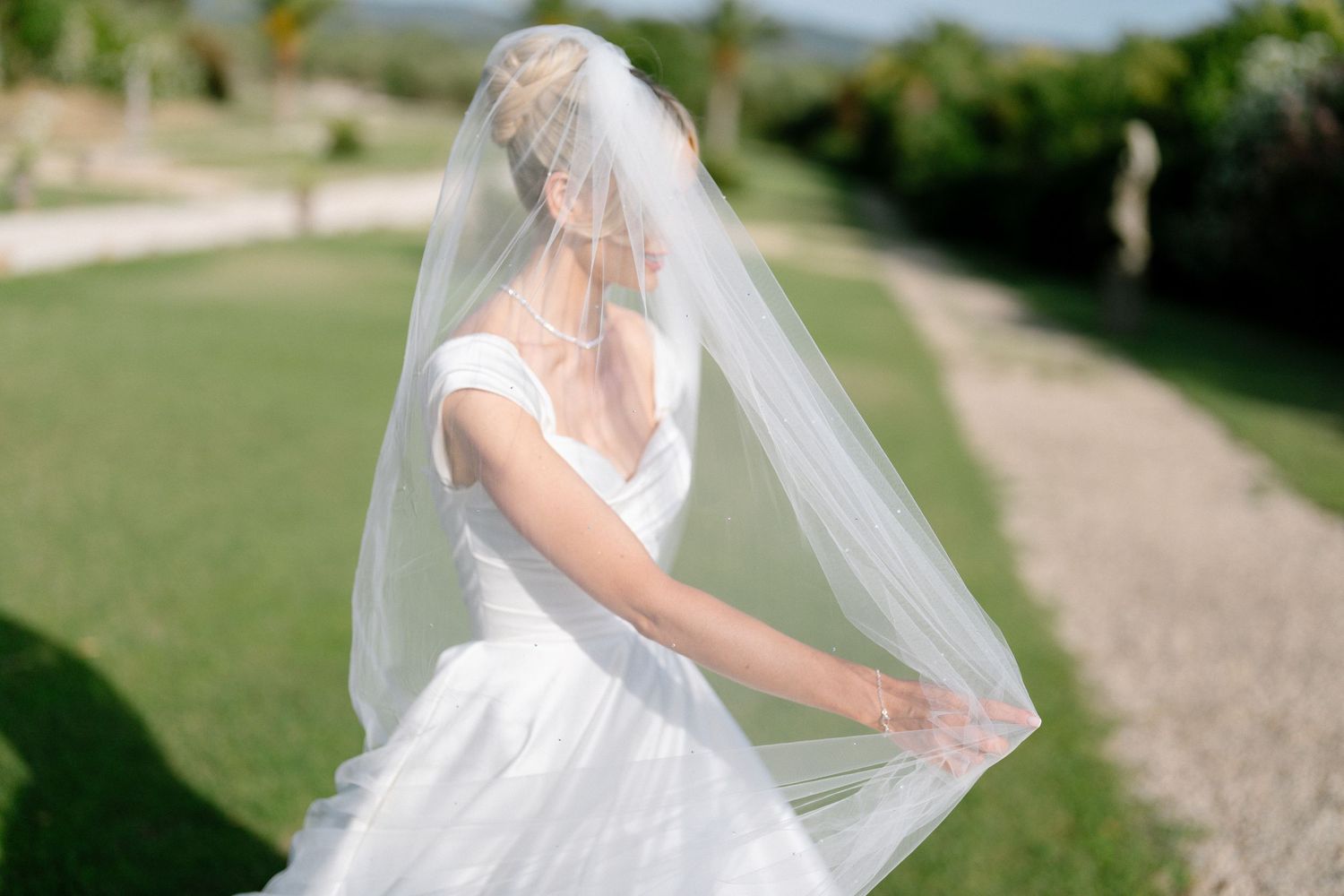 Ethereal bridal portraits with flowing veil in an outdoor garden setting.
