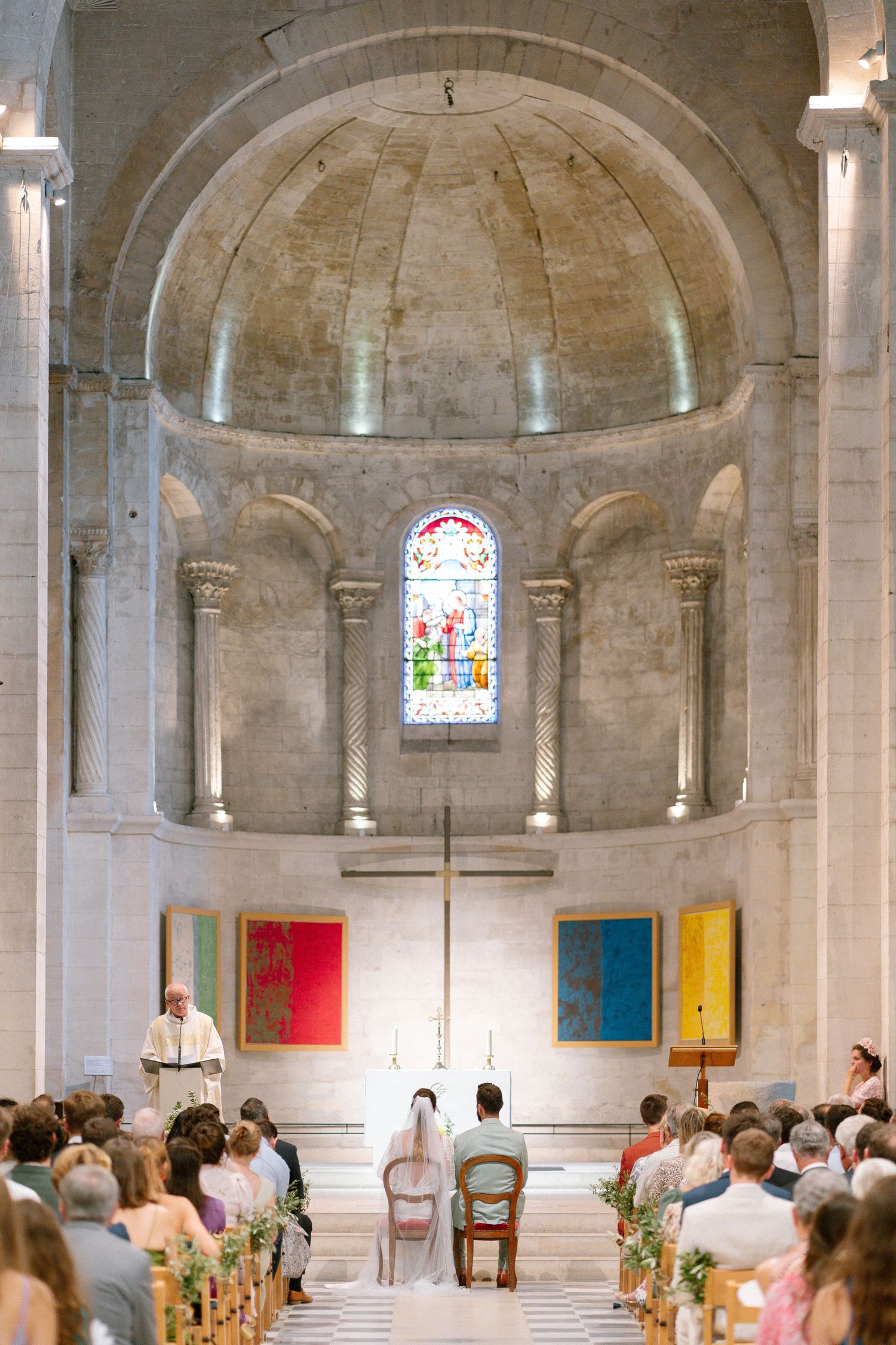 Wedding ceremony in a historic stone church with vaulted ceilings and stained glass windows.