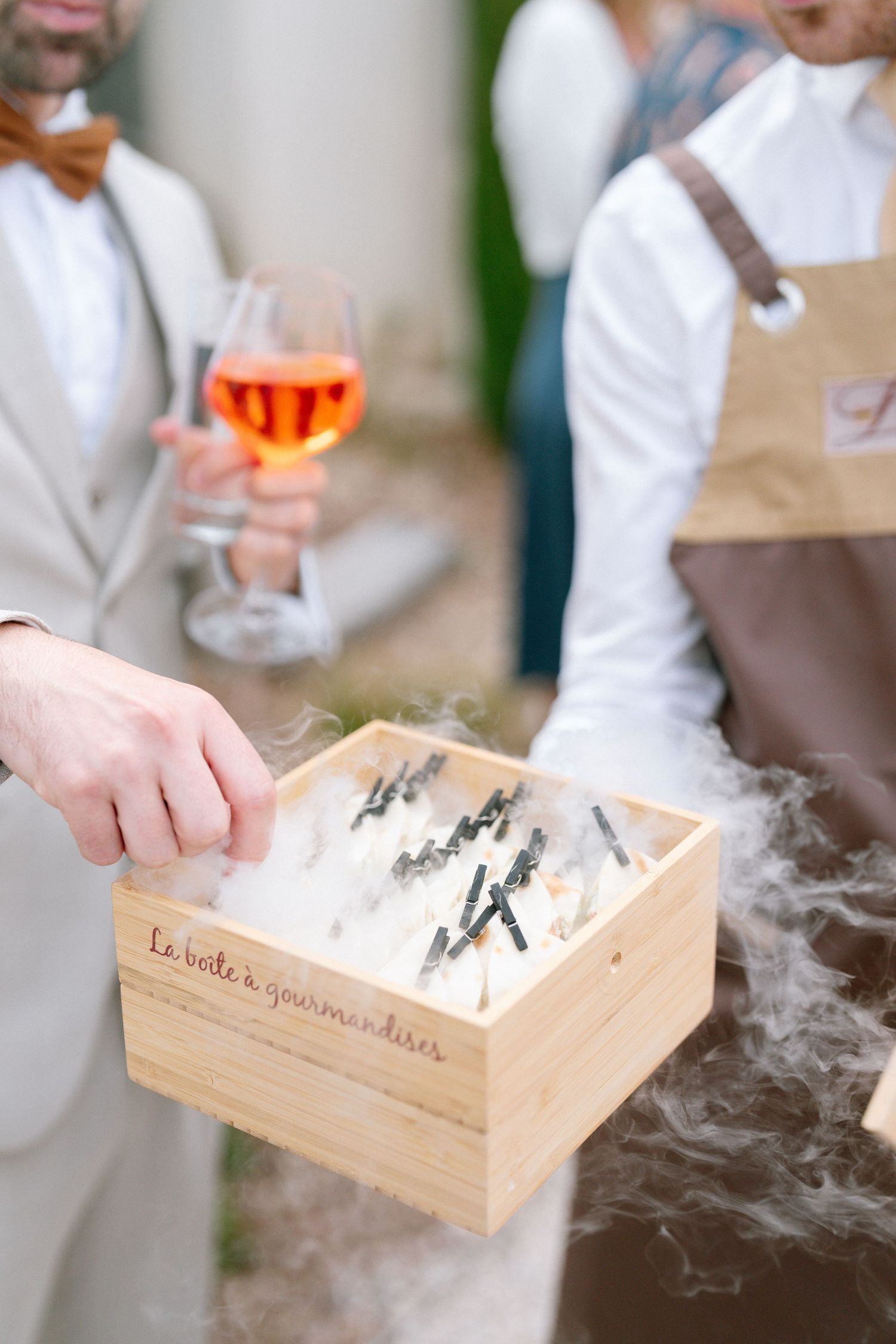 Server presents a wooden box with smoke effects during an elegant wedding reception.
