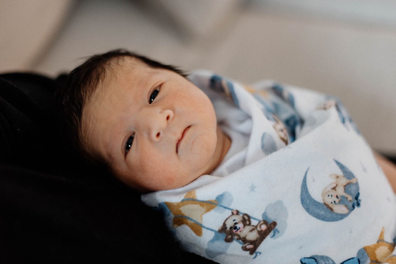 Oakville newborn photographer. capturing newborn swaddled looking lovingly at mother