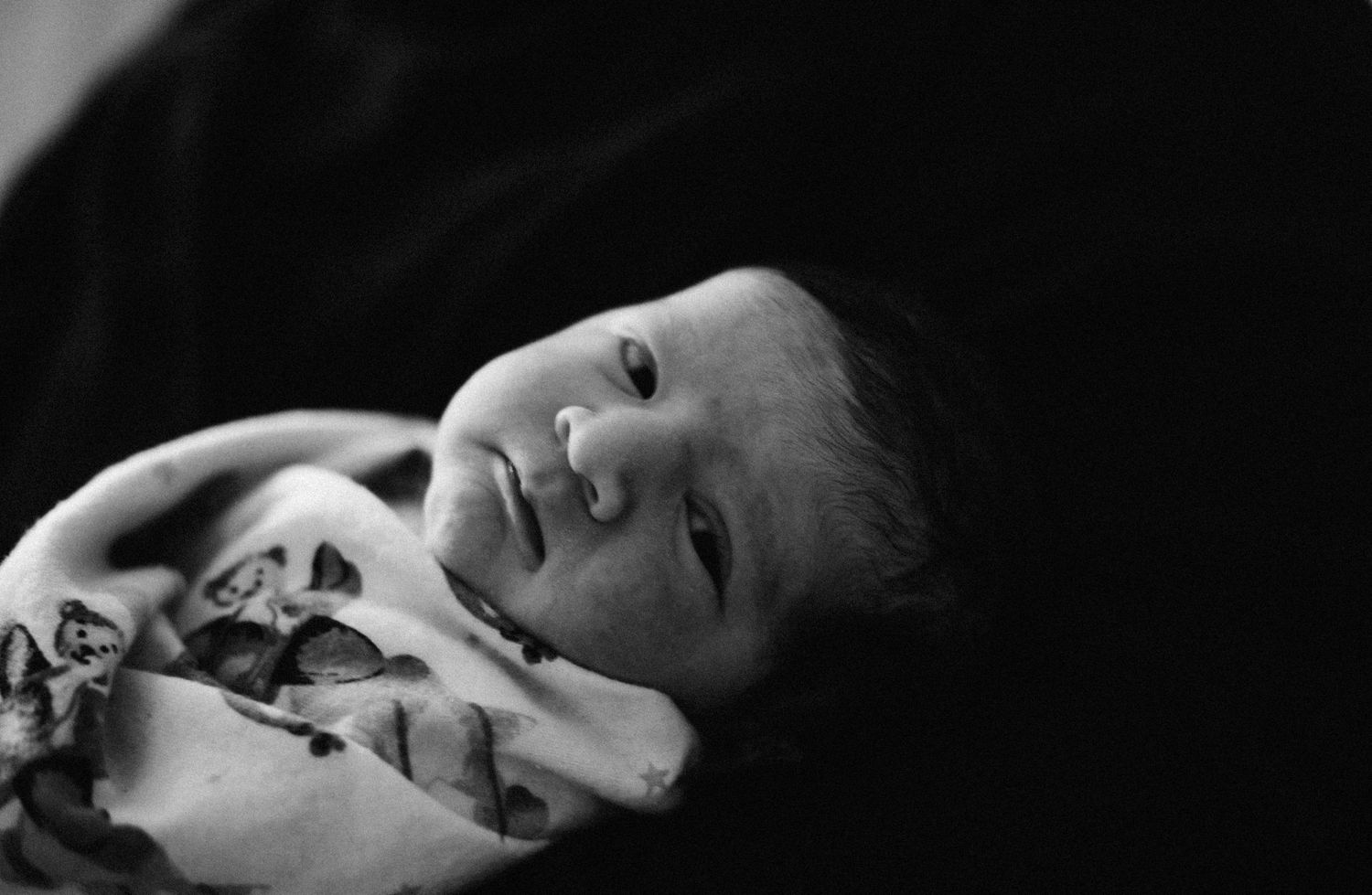 Black and white photo captured by Oakville photographer of newborn looking
