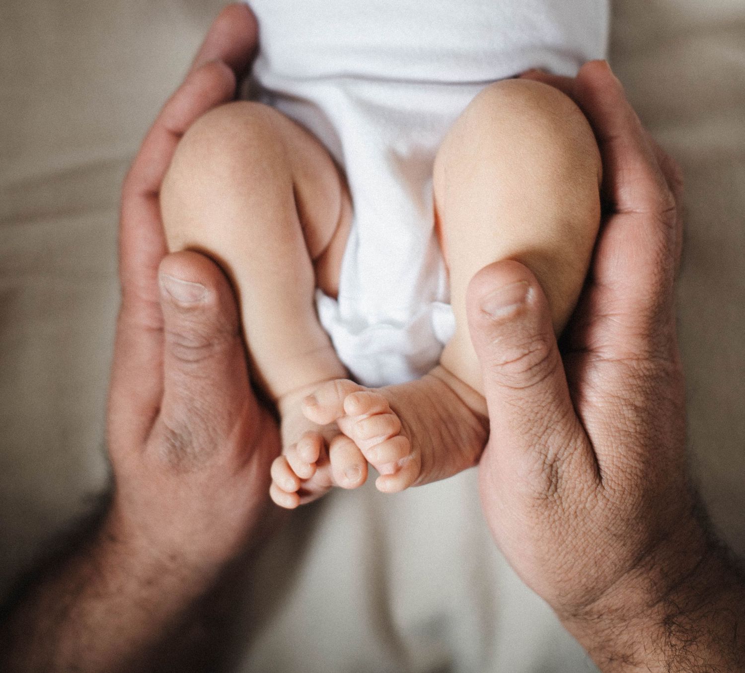 Candid newborn photography moment of father holding baby safely and lovingly