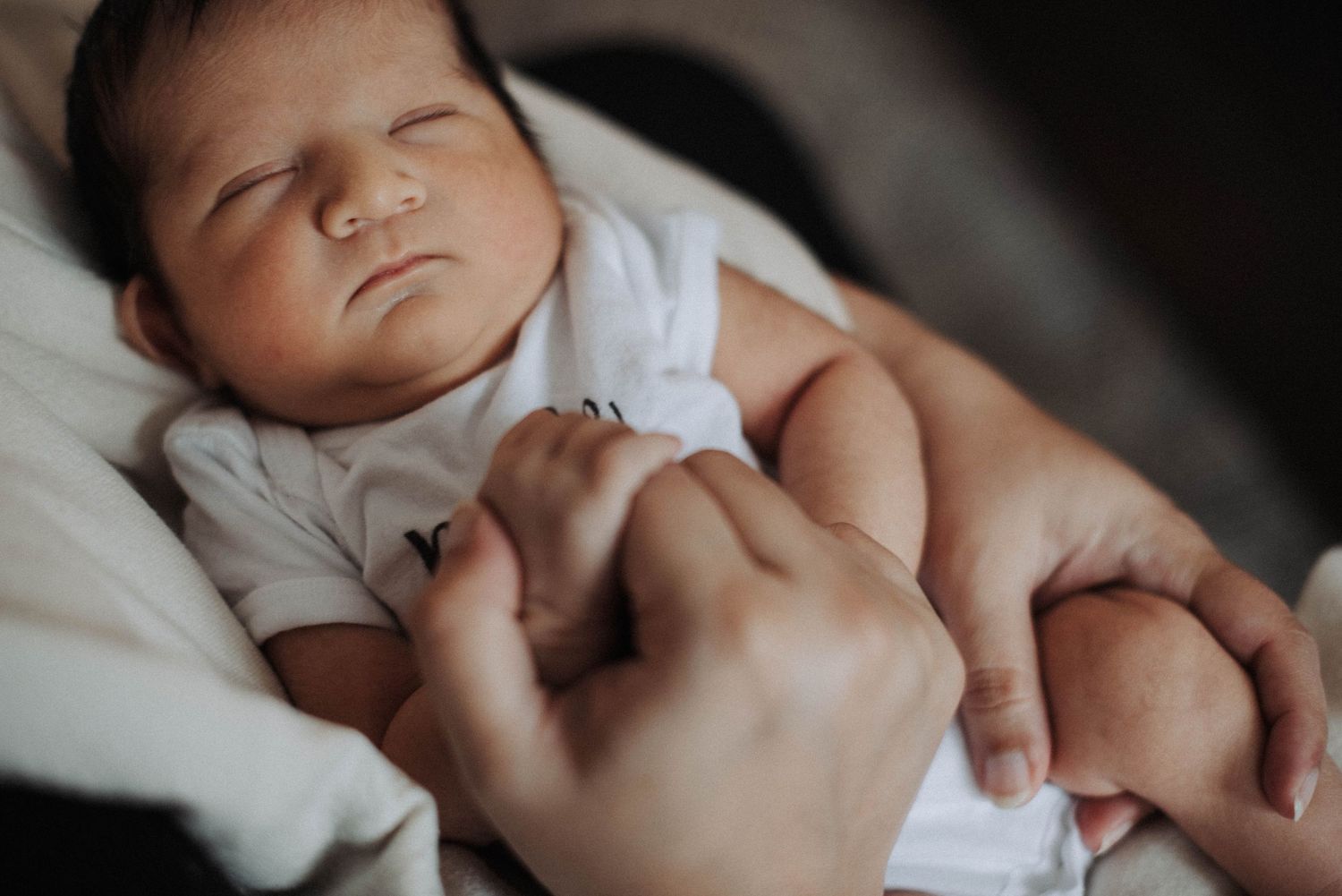 Mississauga in-home newborn photography showing mother holding baby with older brother beside her