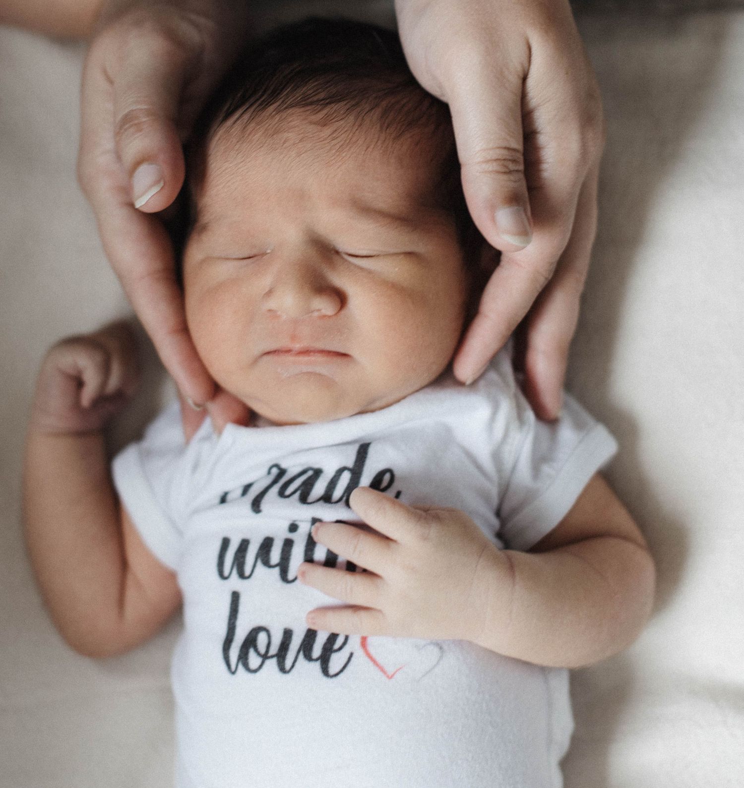 Father gently supporting his baby’s head and legs during an in-home lifestyle newborn photography session