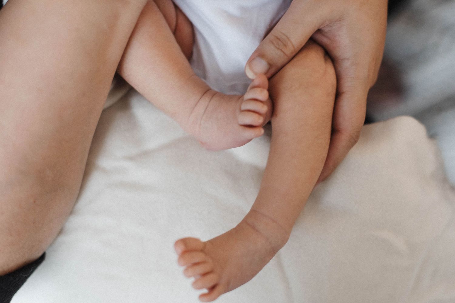 Natural light newborn photography showing mom and baby's tiny legs