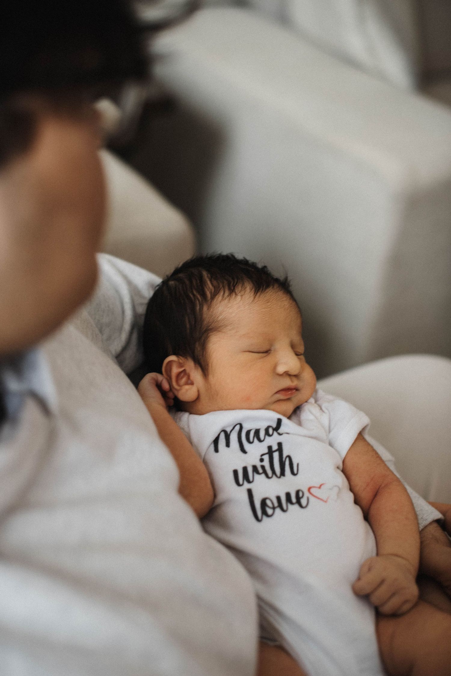 Mississauga in-home newborn photography showing mother holding baby with older brother beside her