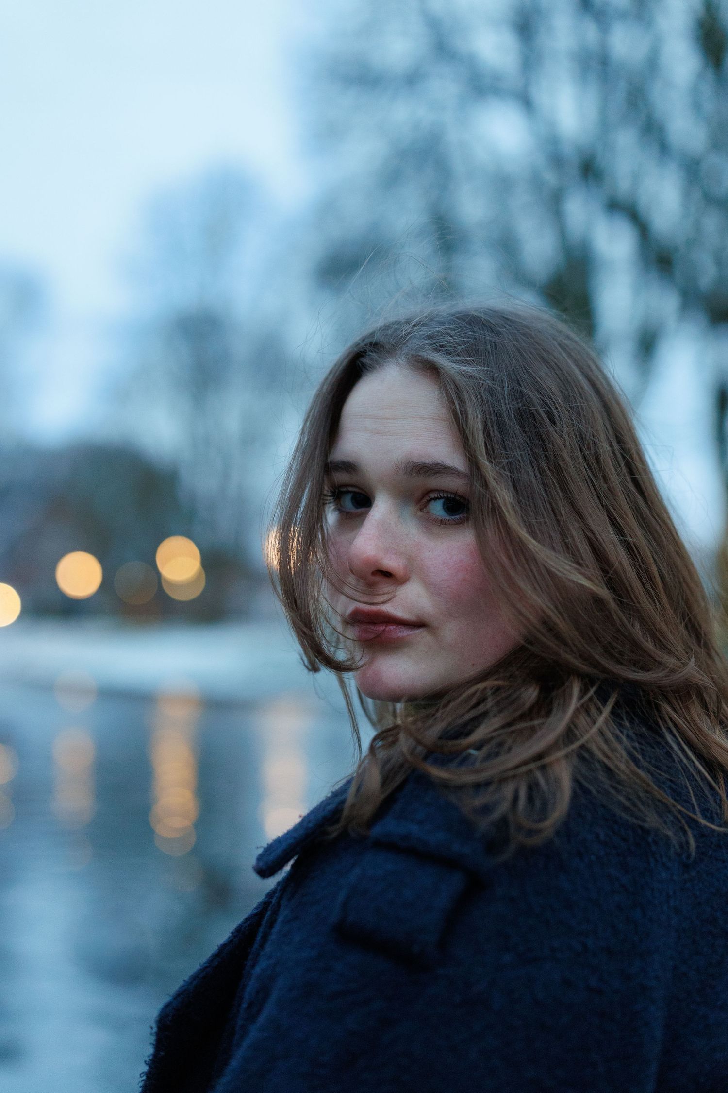 Portretfoto van een vrouw in een winterpark in alphen aan den rijn met sneeuw, vastgelegd met natuurlijk licht.